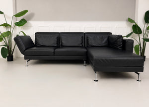 Gebrauchtes schwarzes Brühl Moule Designer Leder Sofa vor einer Wand, stilvoll und modern eingerichtet.