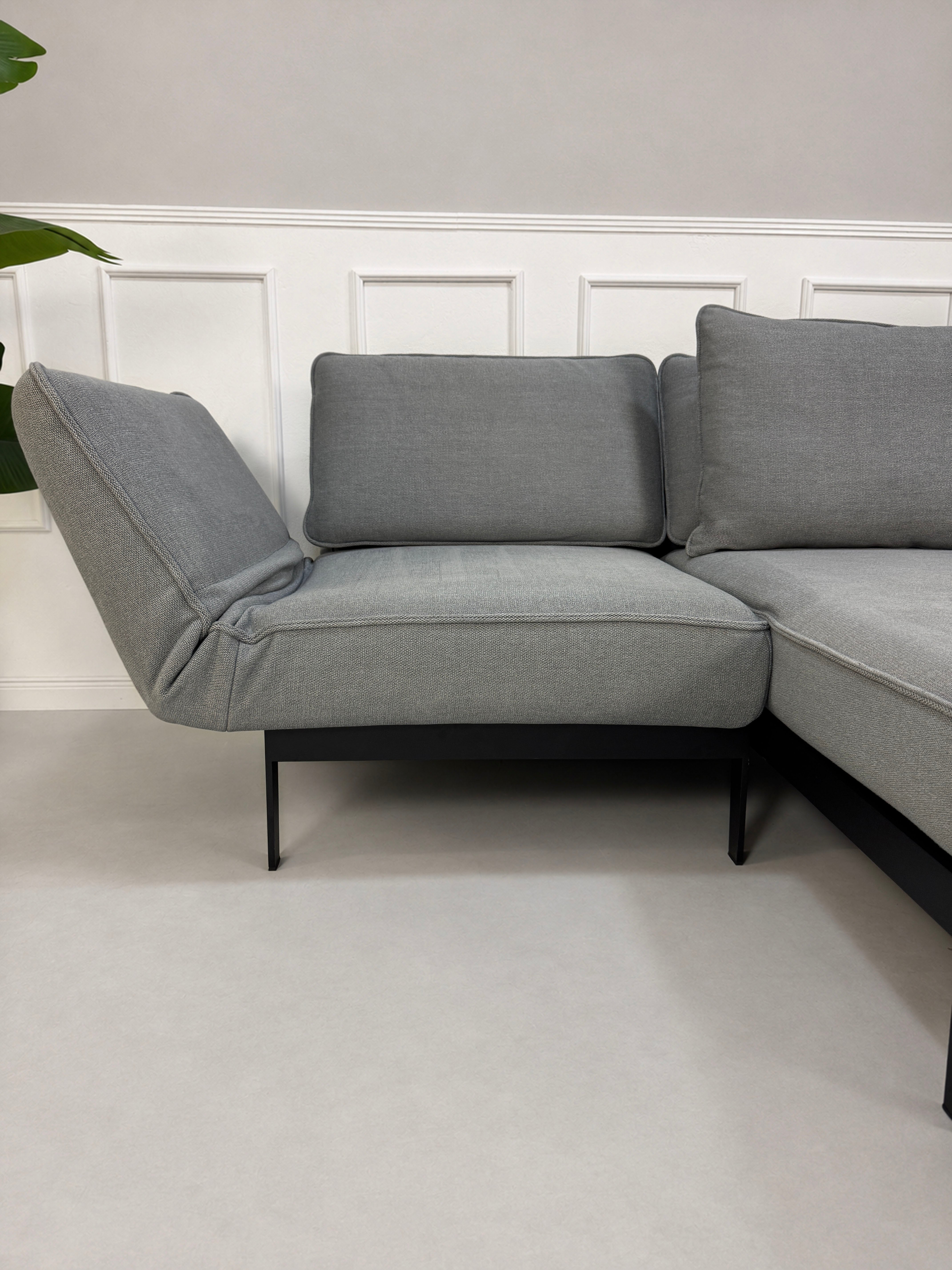 Gebrauchtes graues Rolf Benz Mera Designer Stoff Sofa vor einer Wand, stilvoll und modern eingerichtet.
