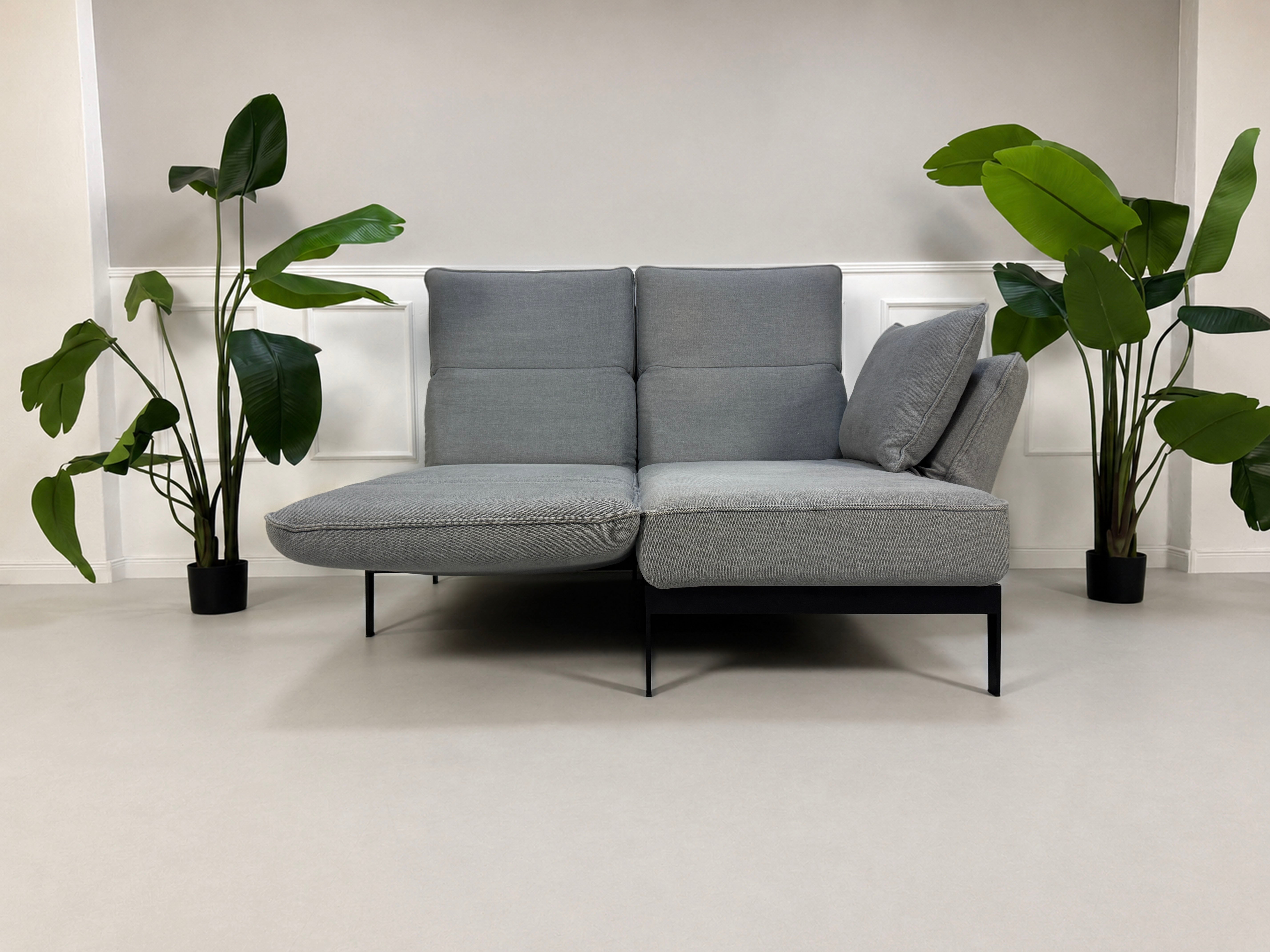 Gebrauchtes graues Rolf Benz Mera Designer Stoff Sofa vor einer Wand, stilvoll und modern eingerichtet.