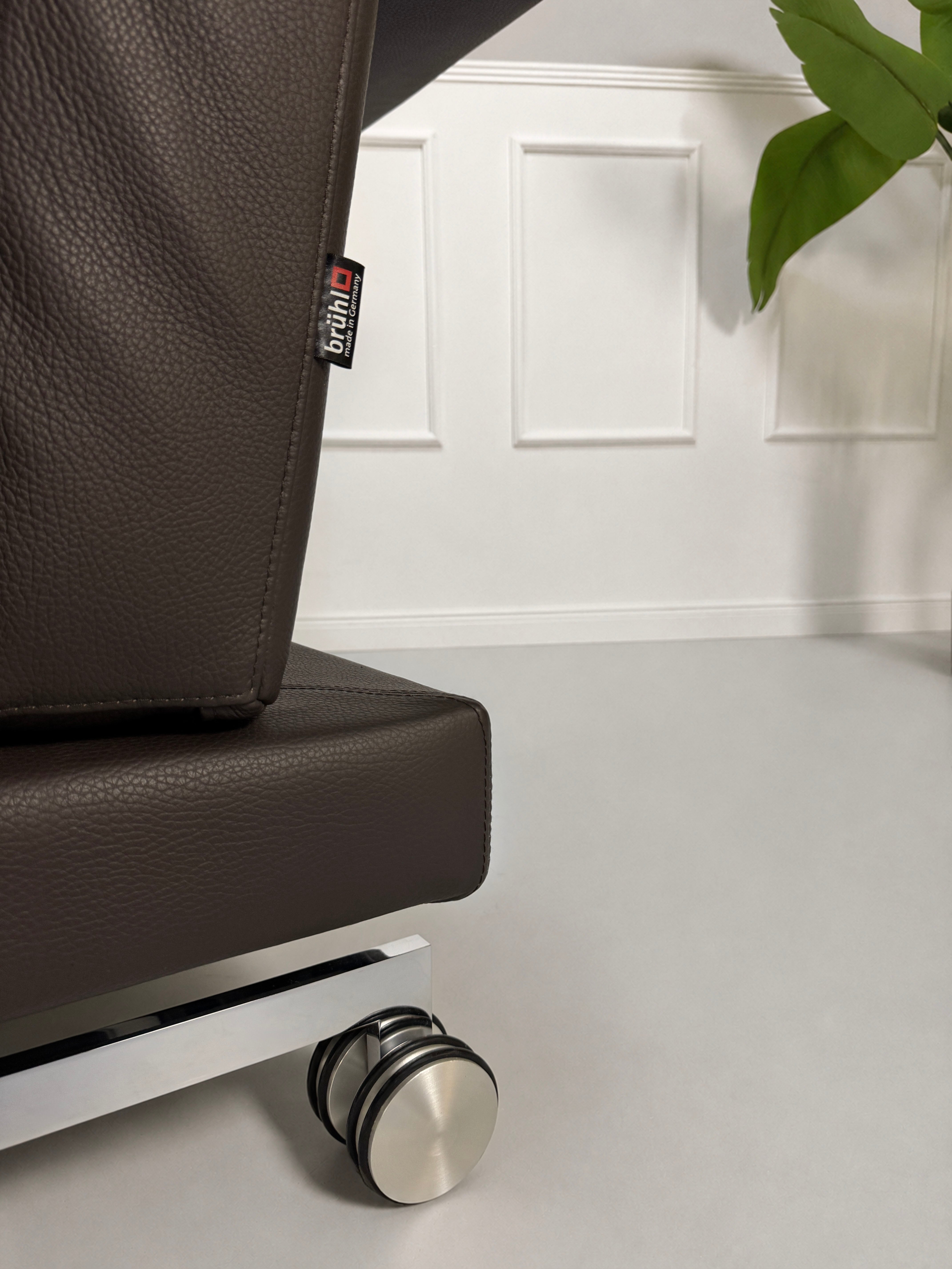 Gebrauchtes braunes Brühl Moule Designer Leder Sofa vor einer Wand, stilvoll und modern eingerichtet.