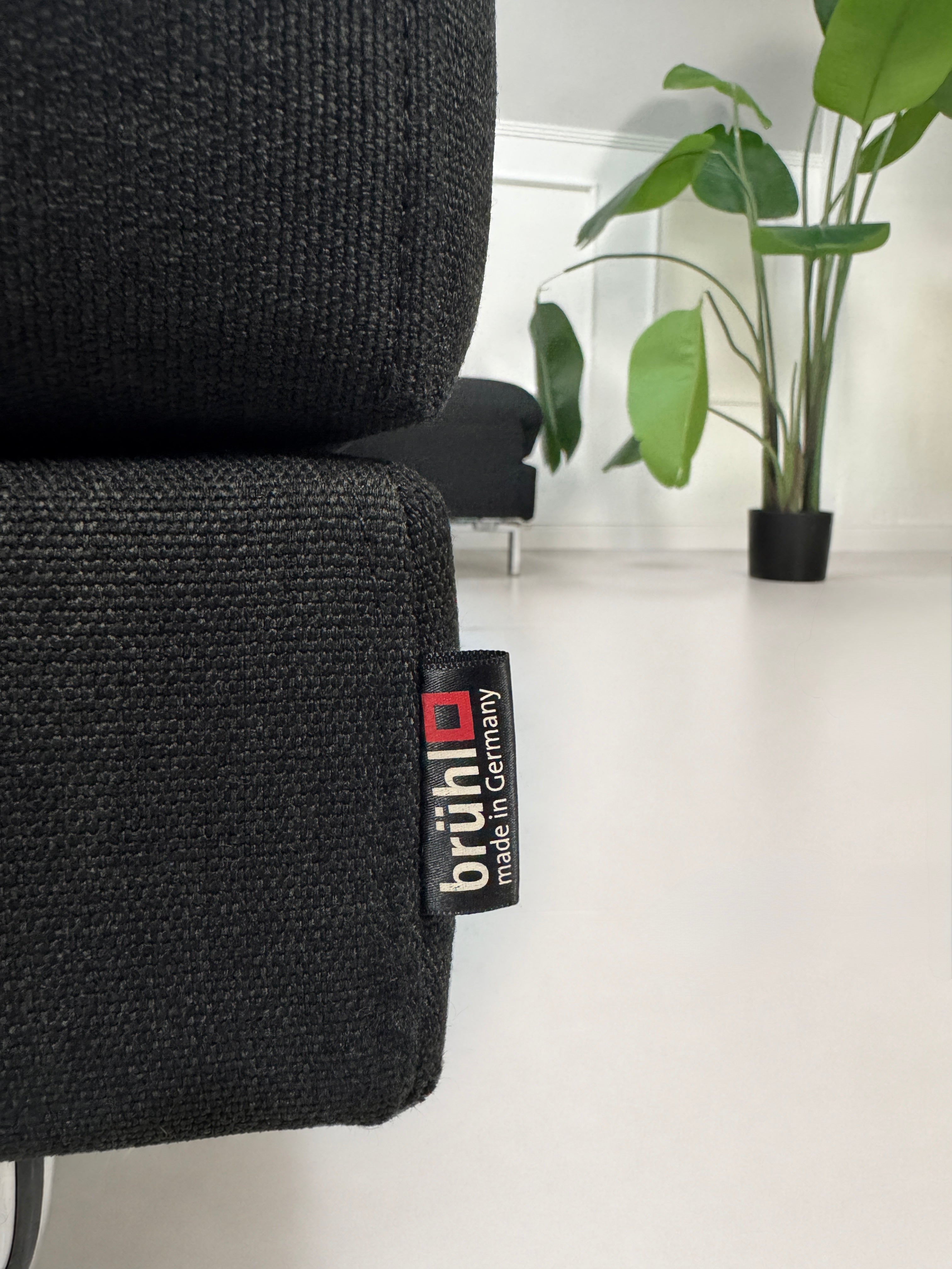 Gebrauchtes schwarzes Brühl Fourtwo Designer Stoff Sofa vor einer Wand, stilvoll und modern eingerichtet.