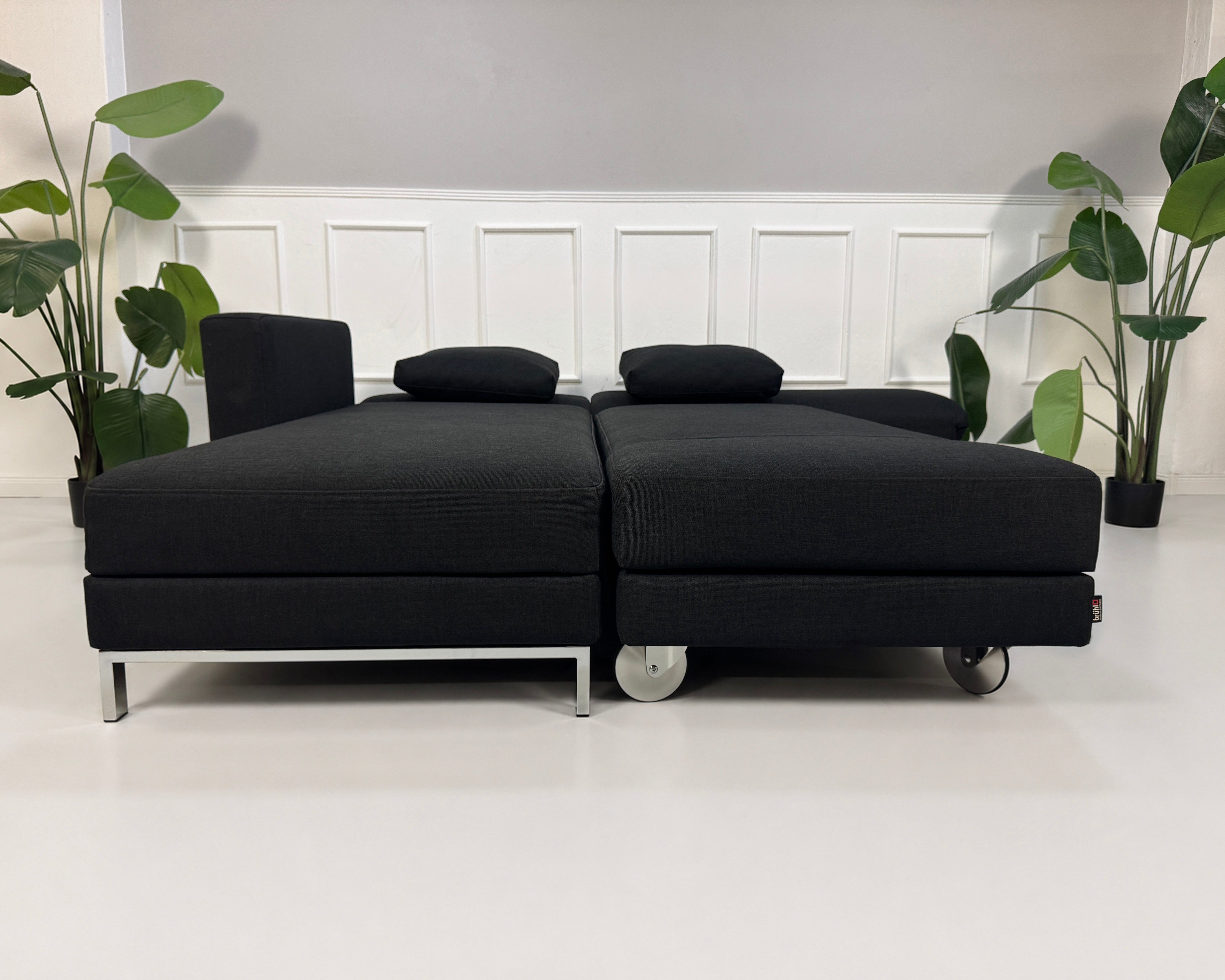 Gebrauchtes schwarzes Brühl Fourtwo Designer Stoff Sofa vor einer Wand, stilvoll und modern eingerichtet.