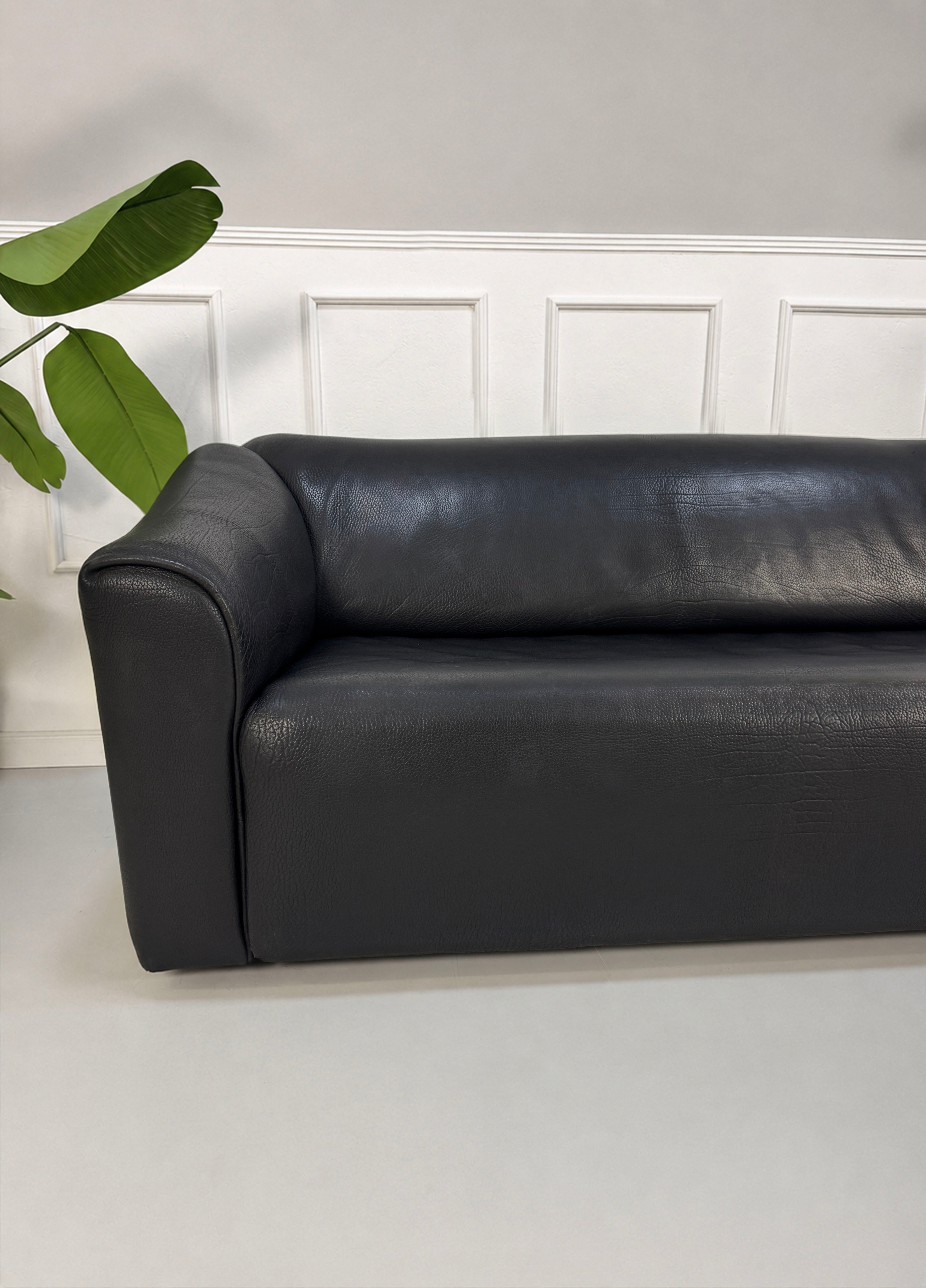 Gebrauchtes schwarzes De Sede DS47 Designer Leder Sofa vor einer Wand, stilvoll und modern eingerichtet.