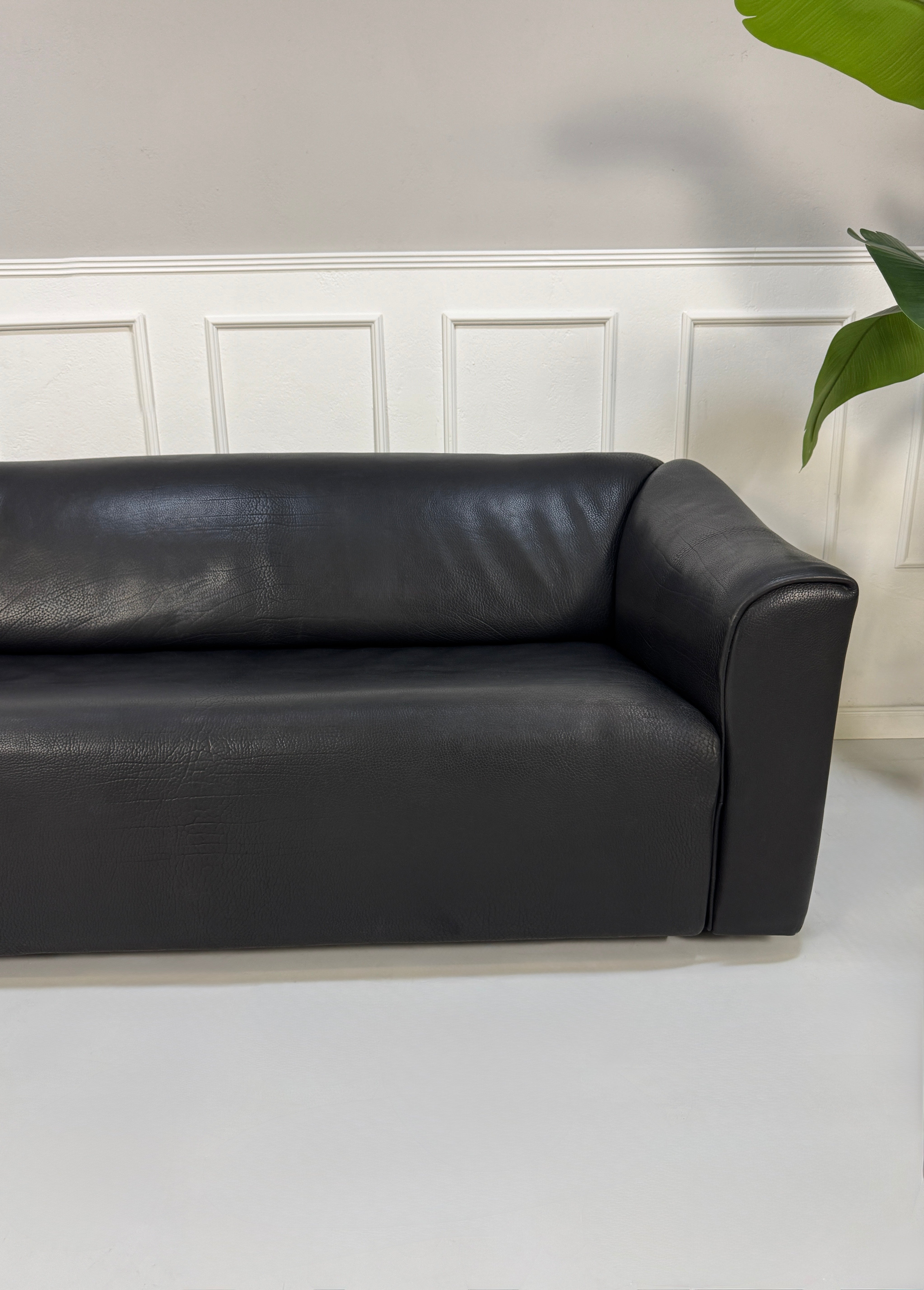 Gebrauchtes schwarzes De Sede DS47 Designer Leder Sofa vor einer Wand, stilvoll und modern eingerichtet.