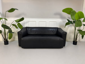 Gebrauchtes schwarzes De Sede DS47 Designer Leder Sofa vor einer Wand, stilvoll und modern eingerichtet.