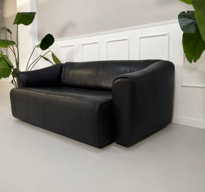 Gebrauchtes schwarzes De Sede DS47 Designer Leder Sofa vor einer Wand, stilvoll und modern eingerichtet.