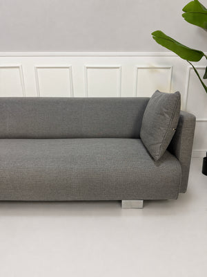 Gebrauchtes graues Rolf Benz 6300 Designer Stoff Sofa vor einer Wand, stilvoll und modern eingerichtet.