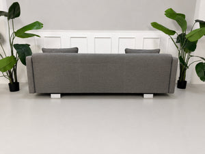 Gebrauchtes graues Rolf Benz 6300 Designer Stoff Sofa vor einer Wand, stilvoll und modern eingerichtet.