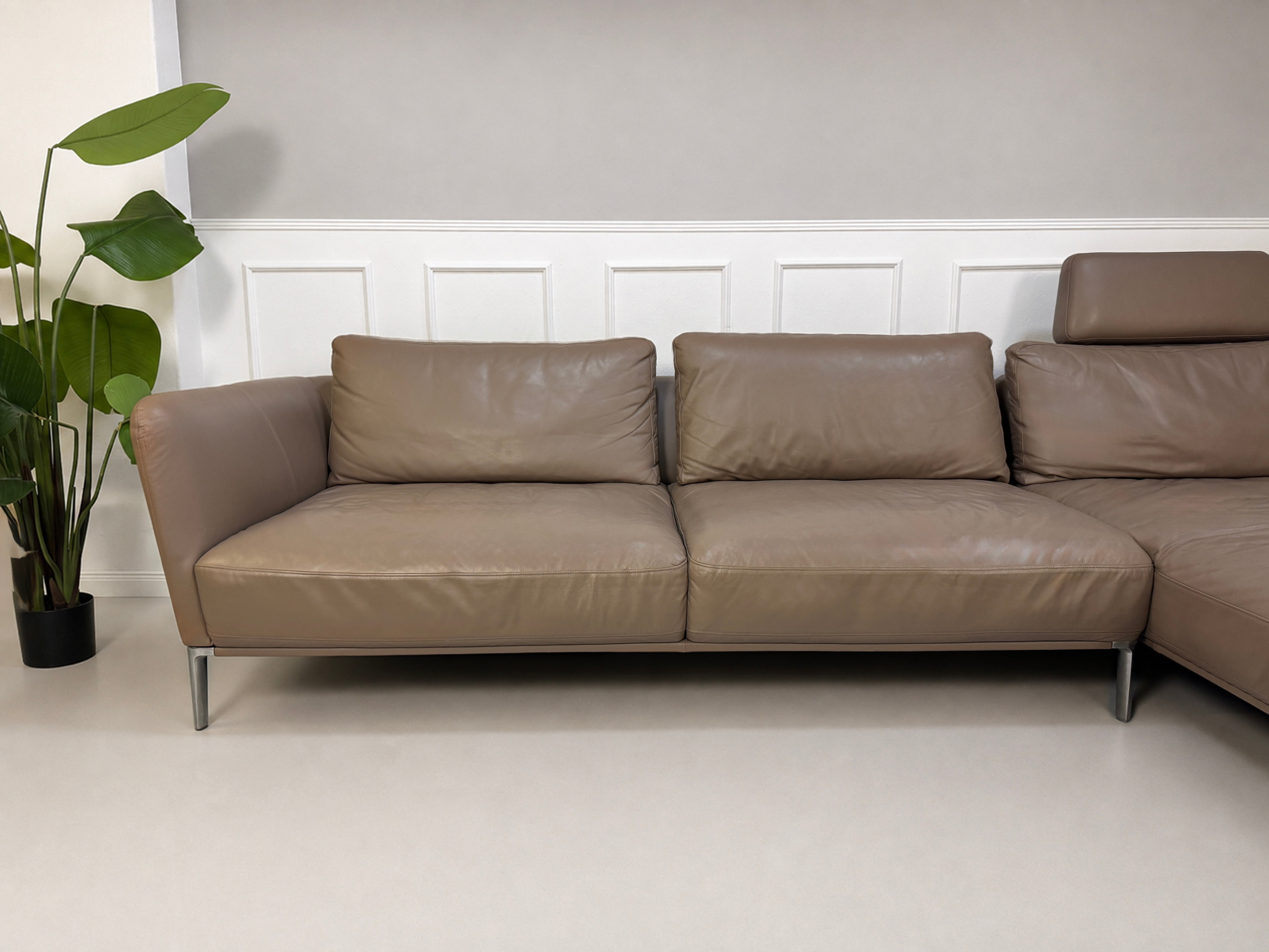 Gebrauchtes Braun Grau Rolf Benz Scala Designer Leder Sofa vor einer Wand, stilvoll und modern eingerichtet.