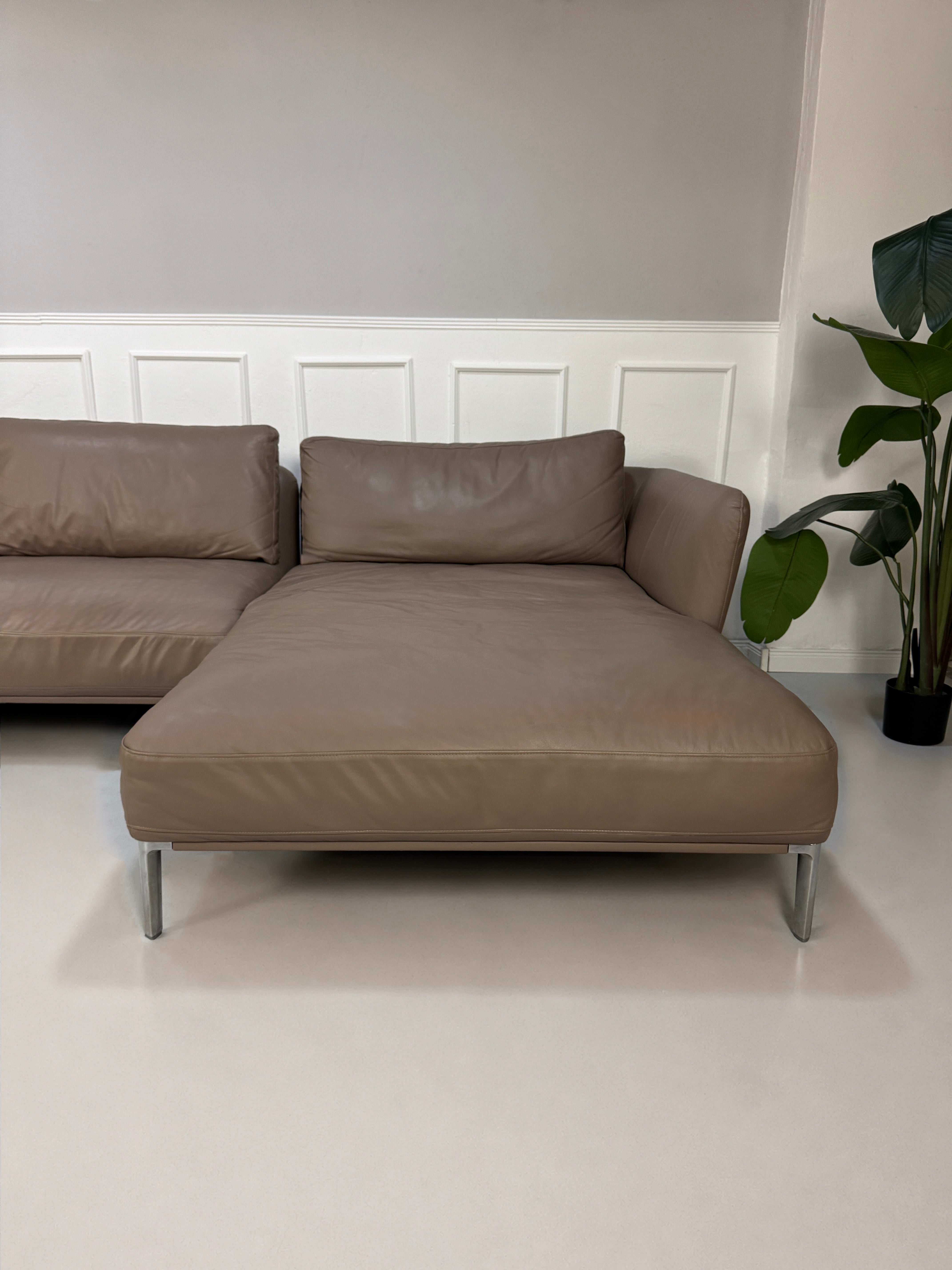 Gebrauchtes Braun Grau Rolf Benz Scala Designer Leder Sofa vor einer Wand, stilvoll und modern eingerichtet.