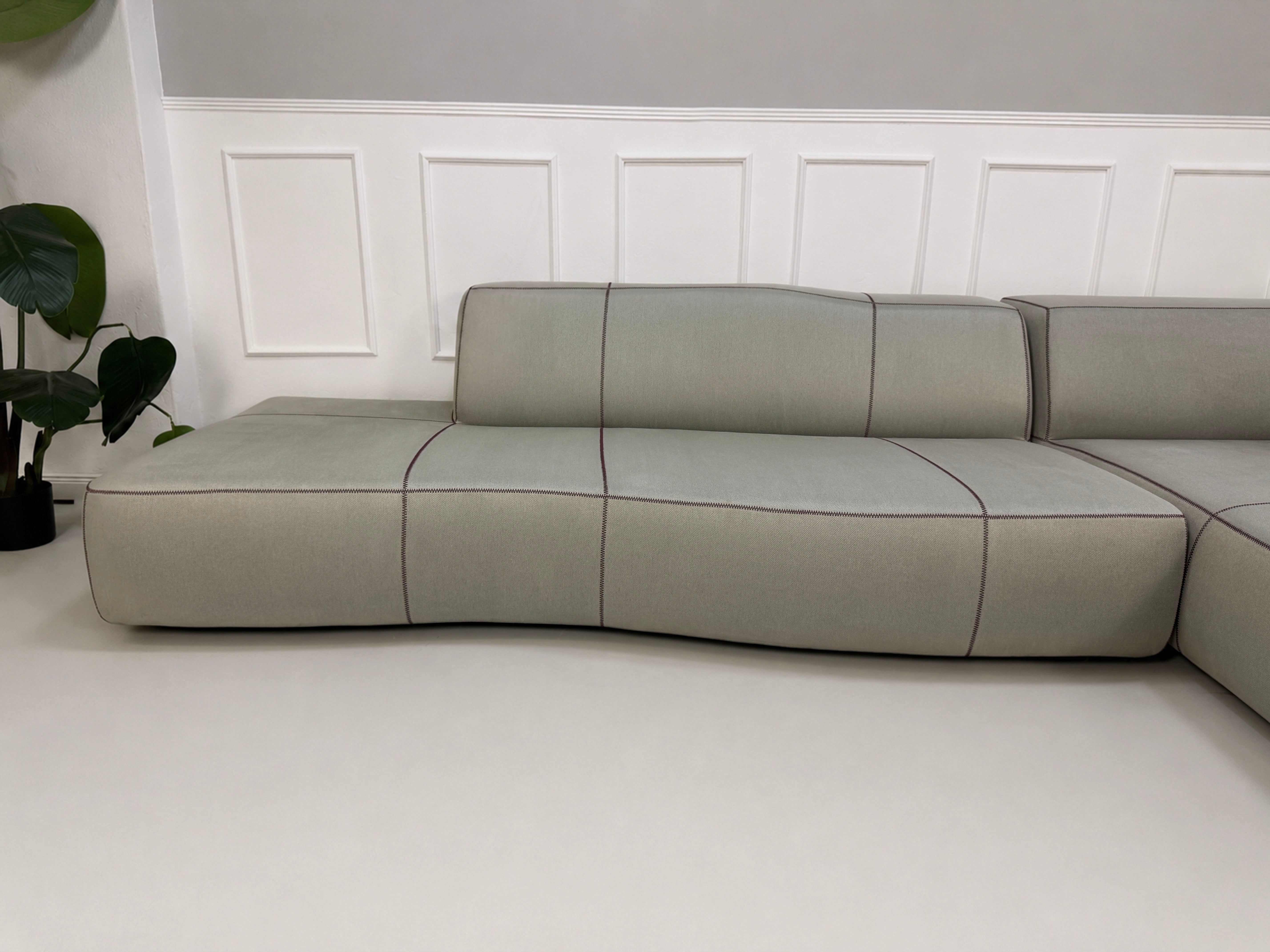 Gebrauchtes graues BB Italia Bend Designer Stoff Sofa vor einer Wand, stilvoll und modern eingerichtet.