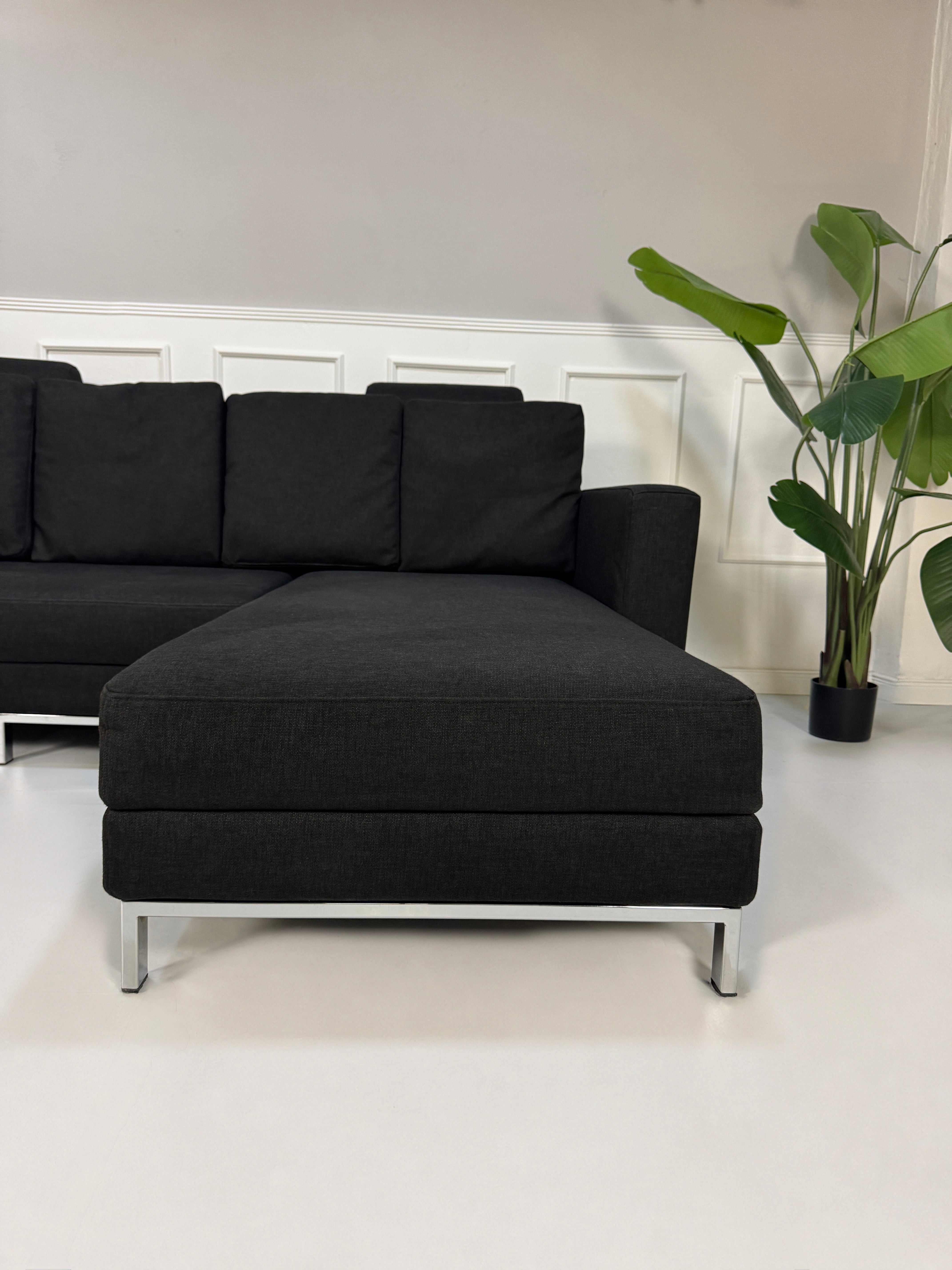 Gebrauchtes schwarzes Brühl Fourtwo Designer Stoff Sofa vor einer Wand, stilvoll und modern eingerichtet.