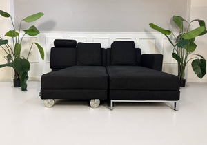 Gebrauchtes schwarzes Brühl Fourtwo Designer Stoff Sofa vor einer Wand, stilvoll und modern eingerichtet.