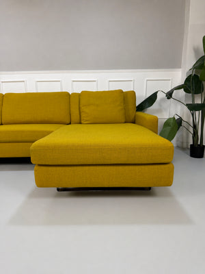 Gelbes Ausstellungsstück COR Conseta Designer Stoff Sofa vor einer Wand, stilvoll und modern eingerichtet.