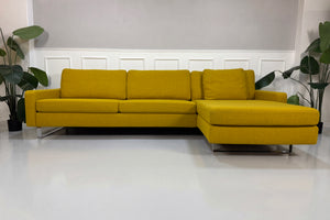 Gelbes Ausstellungsstück COR Conseta Designer Stoff Sofa vor einer Wand, stilvoll und modern eingerichtet.