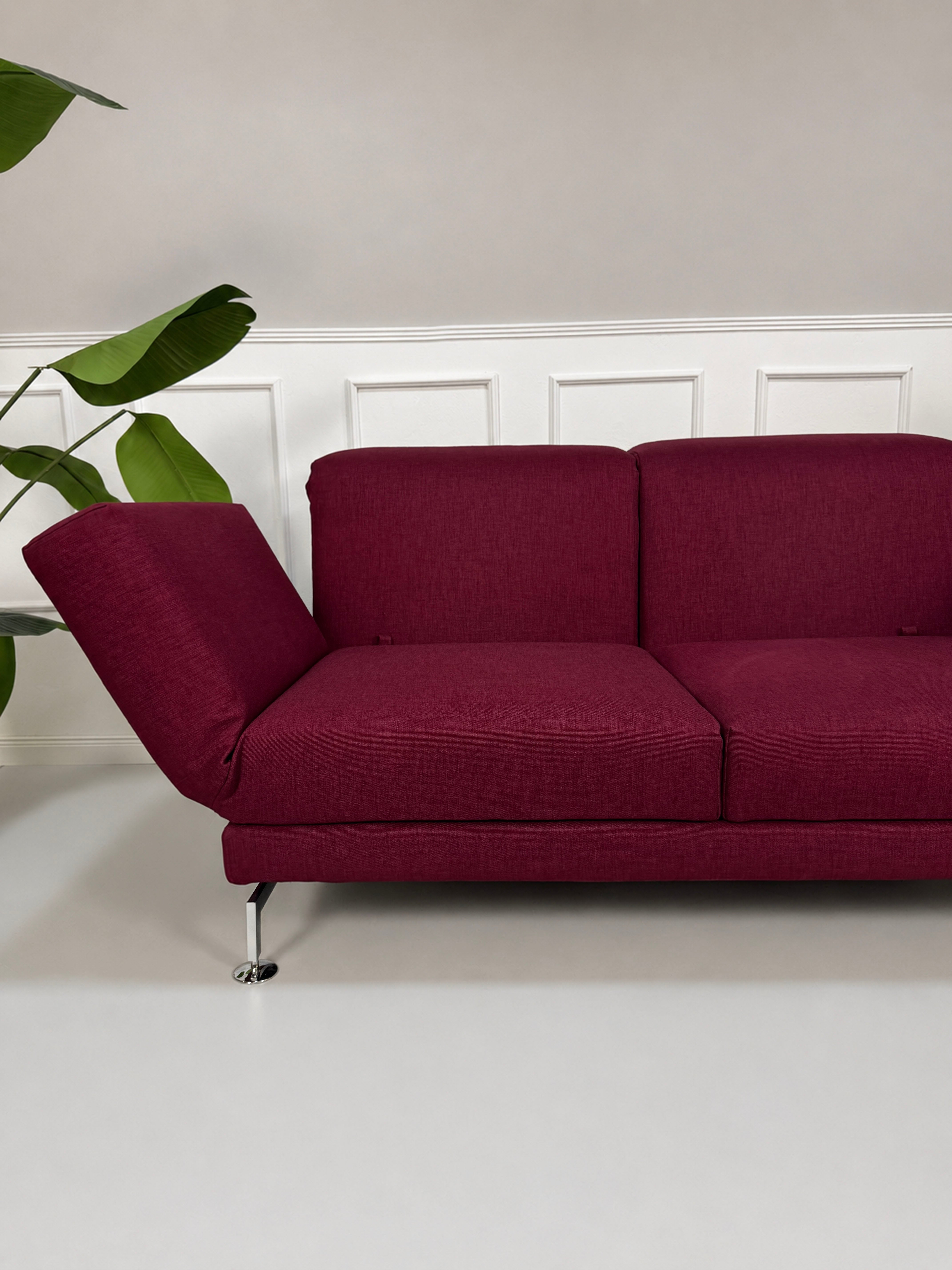 Gebrauchtes rotes Brühl Moule Designer Stoff Sofa vor einer Wand, stilvoll und modern eingerichtet.