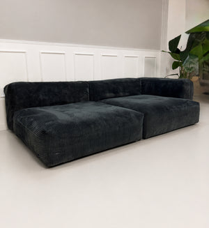 Gebrauchtes graues Vetsak Designer Stoff Sofa vor einer Wand, stilvoll und modern eingerichtet.