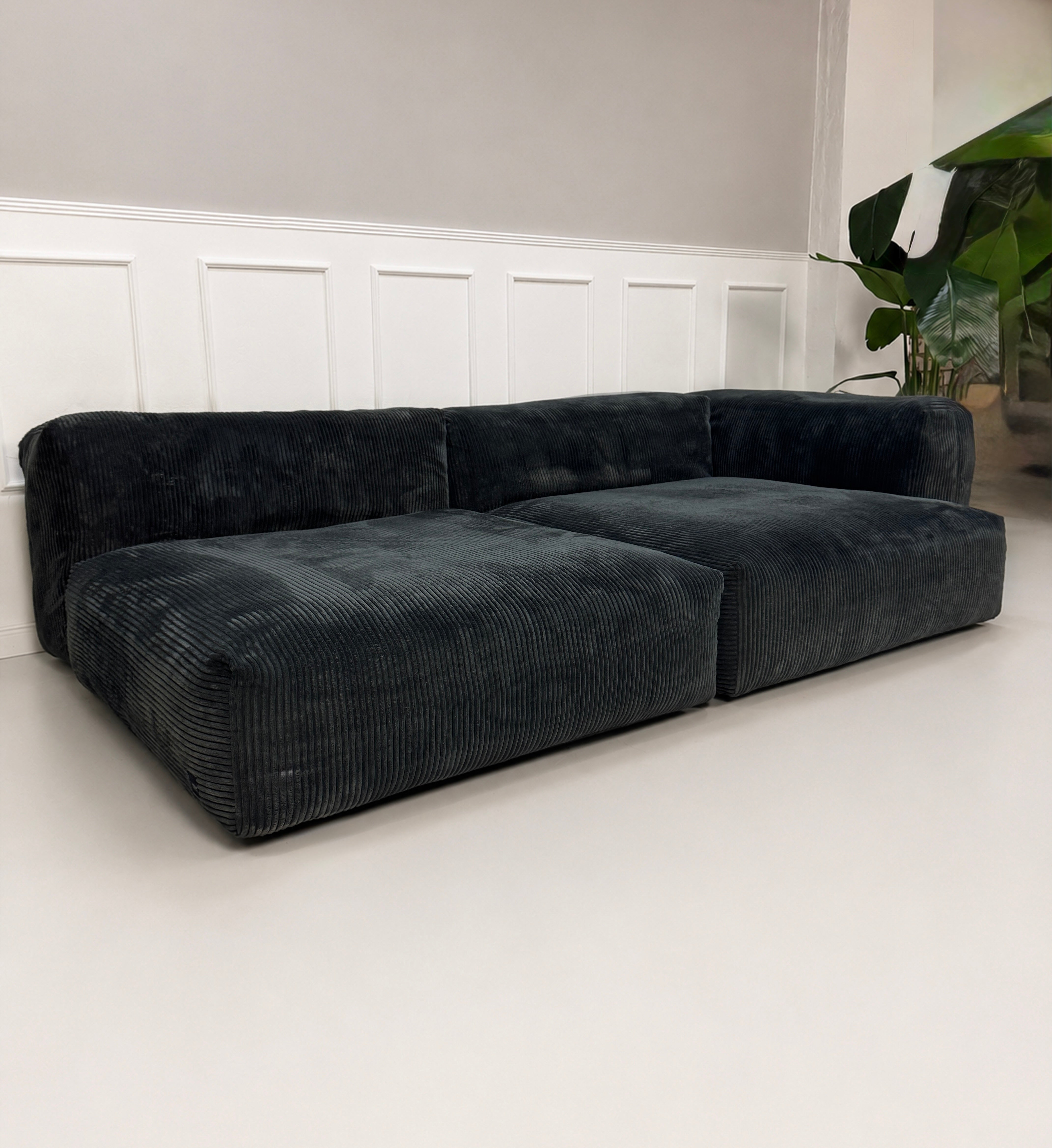 Gebrauchtes graues Vetsak Designer Stoff Sofa vor einer Wand, stilvoll und modern eingerichtet.