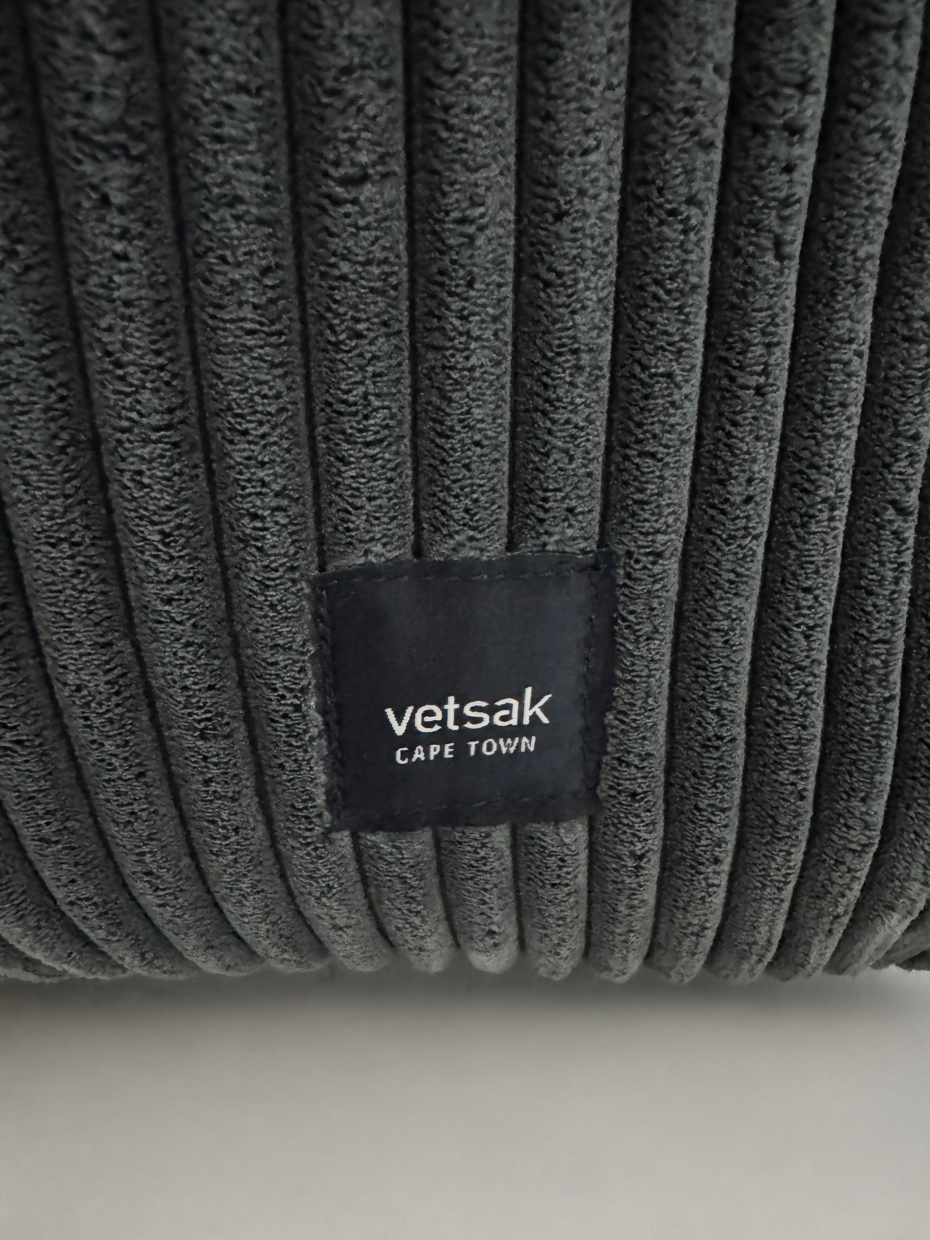 Gebrauchtes graues Vetsak Designer Stoff Sofa vor einer Wand, stilvoll und modern eingerichtet.