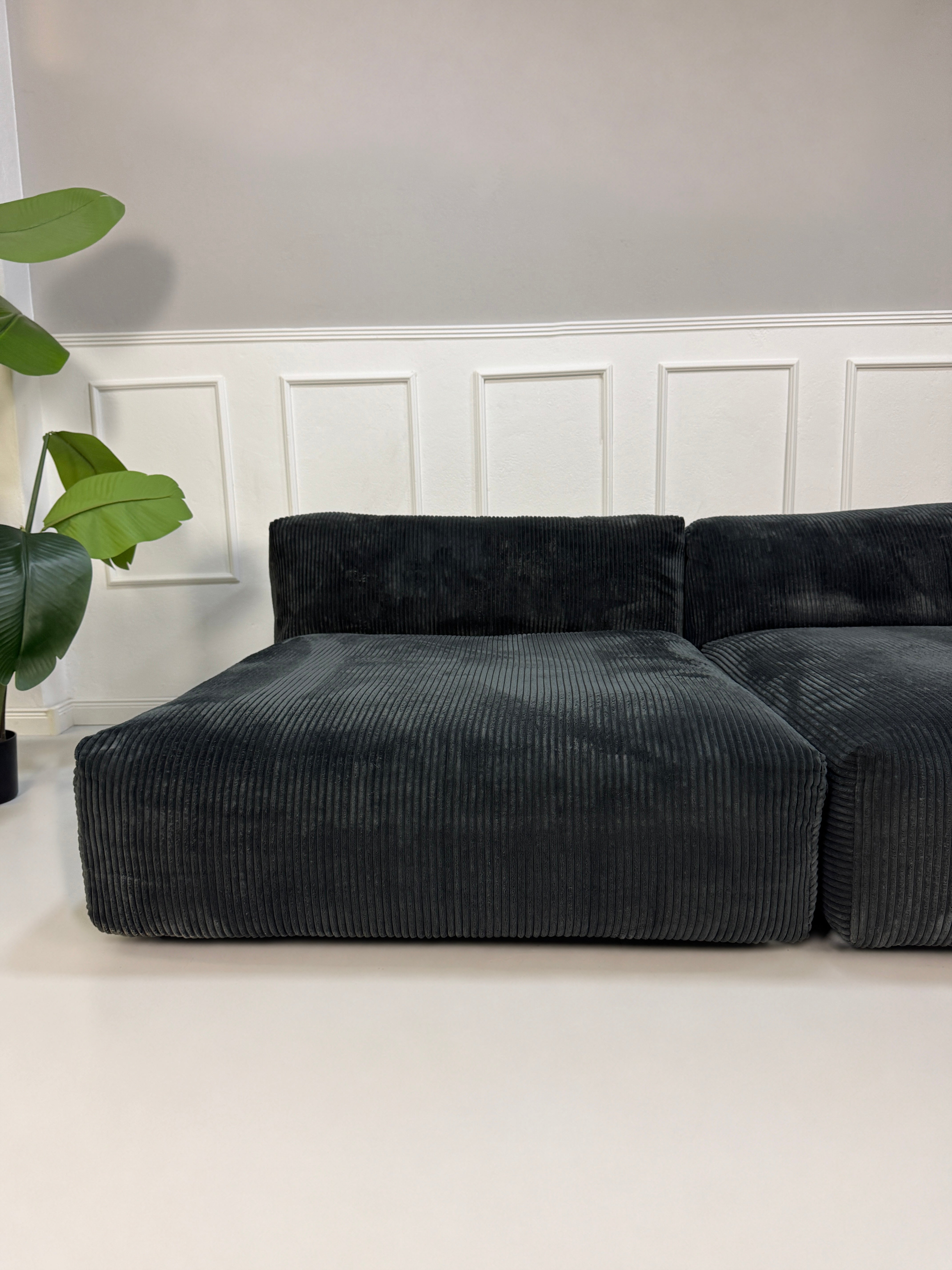 Gebrauchtes graues Vetsak Designer Stoff Sofa vor einer Wand, stilvoll und modern eingerichtet.
