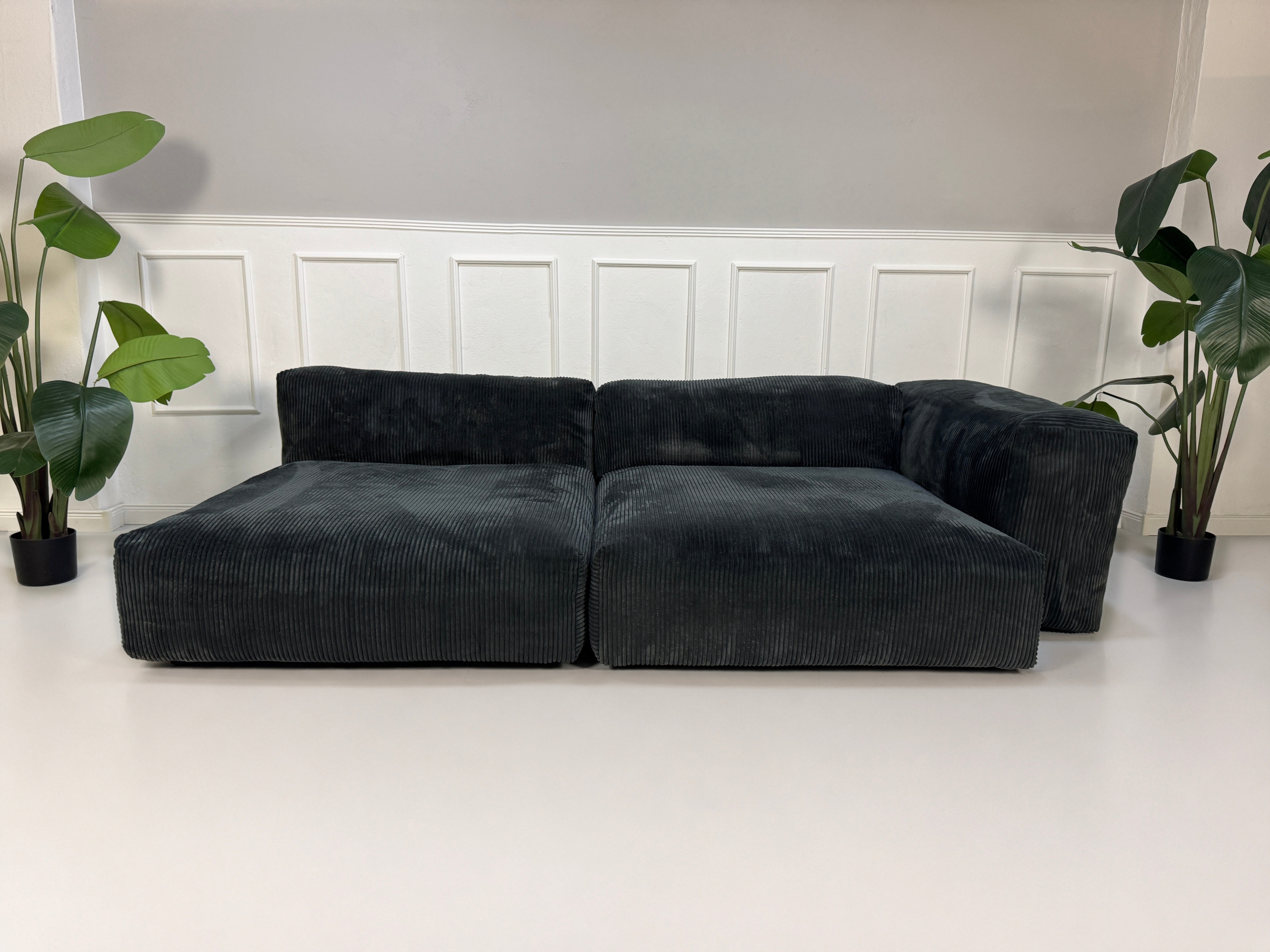 Gebrauchtes graues Vetsak Designer Stoff Sofa vor einer Wand, stilvoll und modern eingerichtet.