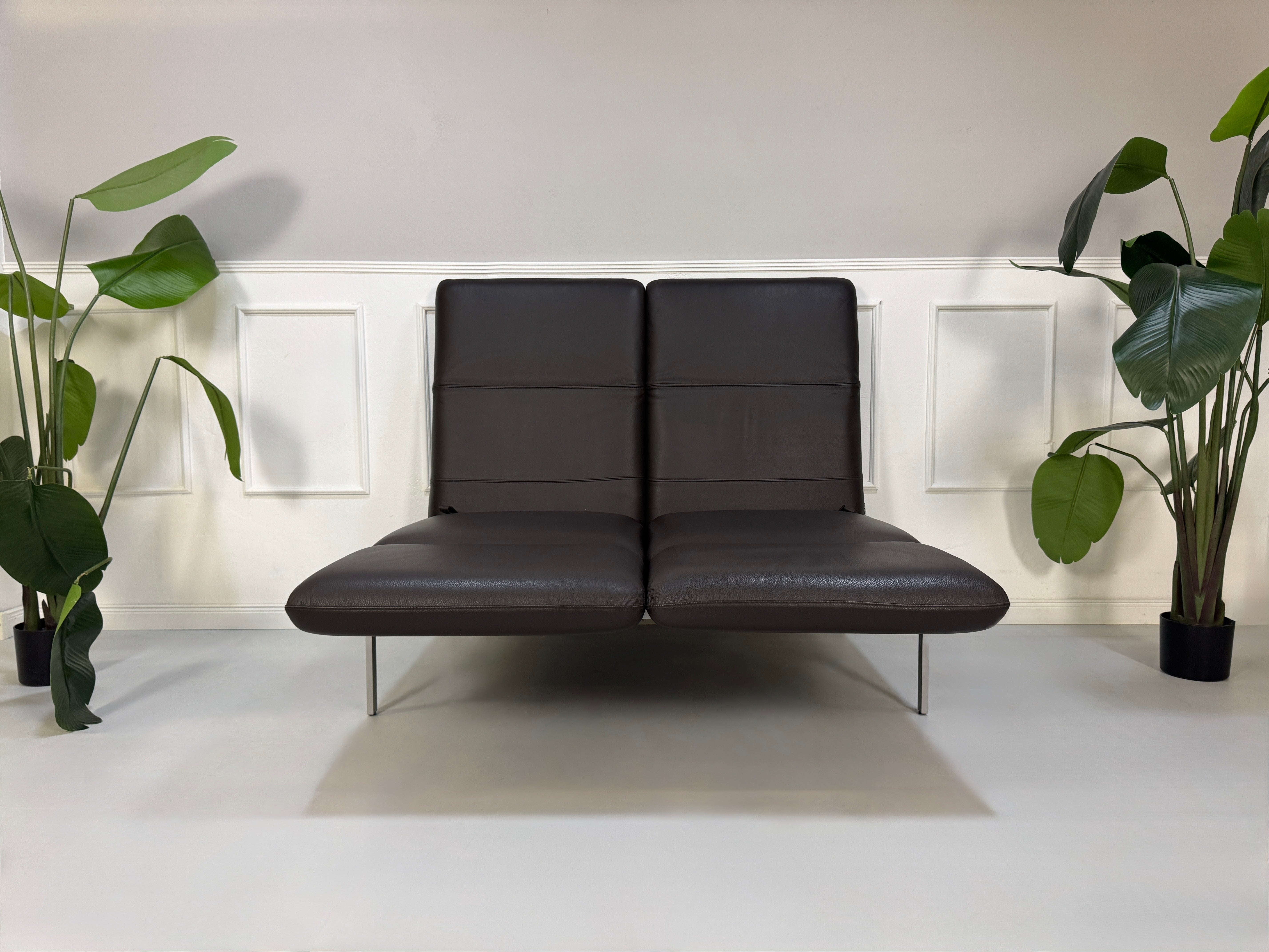 Gebrauchte braune Brühl Roro Designer Leder Sofas vor einer Wand, stilvoll und modern eingerichtet.