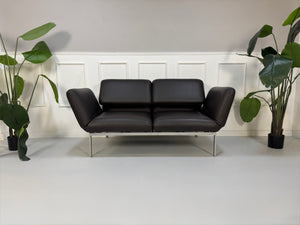 Gebrauchte braune Brühl Roro Designer Leder Sofas vor einer Wand, stilvoll und modern eingerichtet.
