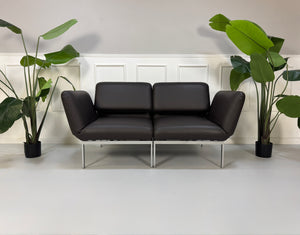Gebrauchte braune Brühl Roro Designer Leder Sofas vor einer Wand, stilvoll und modern eingerichtet.