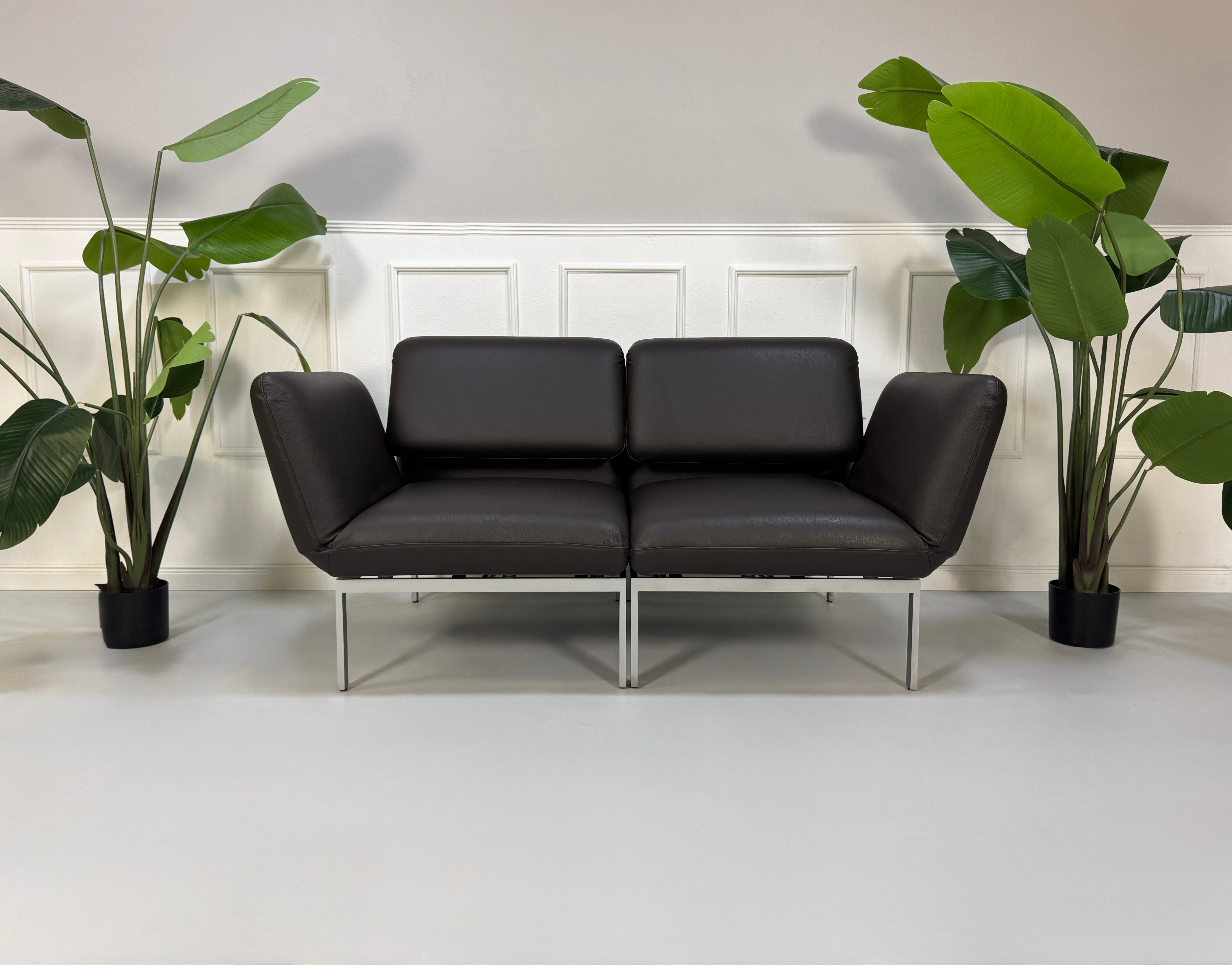 Gebrauchte braune Brühl Roro Designer Leder Sofas vor einer Wand, stilvoll und modern eingerichtet.