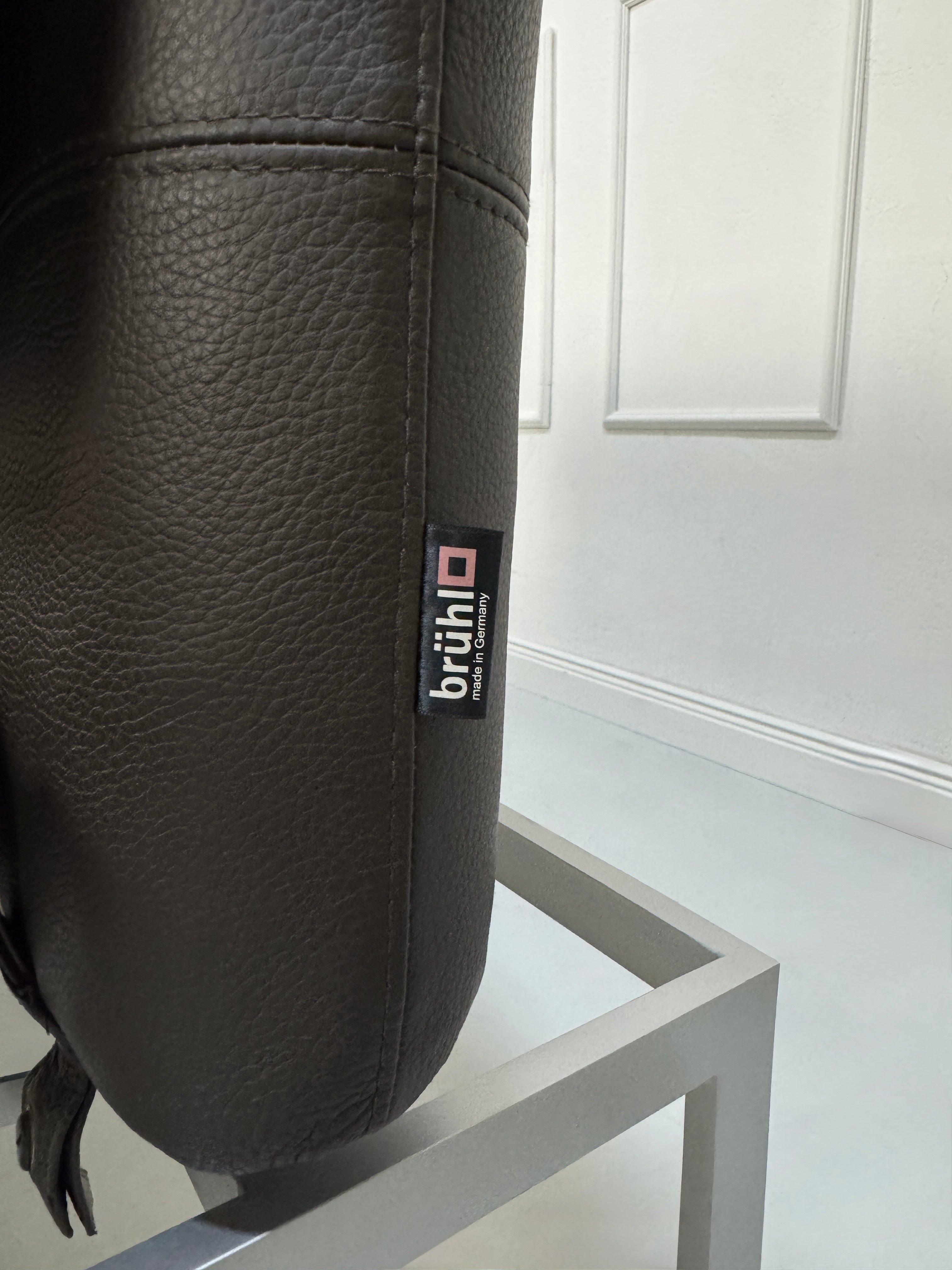 Gebrauchte braune Brühl Roro Designer Leder Sofas vor einer Wand, stilvoll und modern eingerichtet.