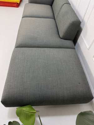 Gebrauchtes graues Muuto In Situ Designer Stoff Sofa vor einer Wand, stilvoll und modern eingerichtet.