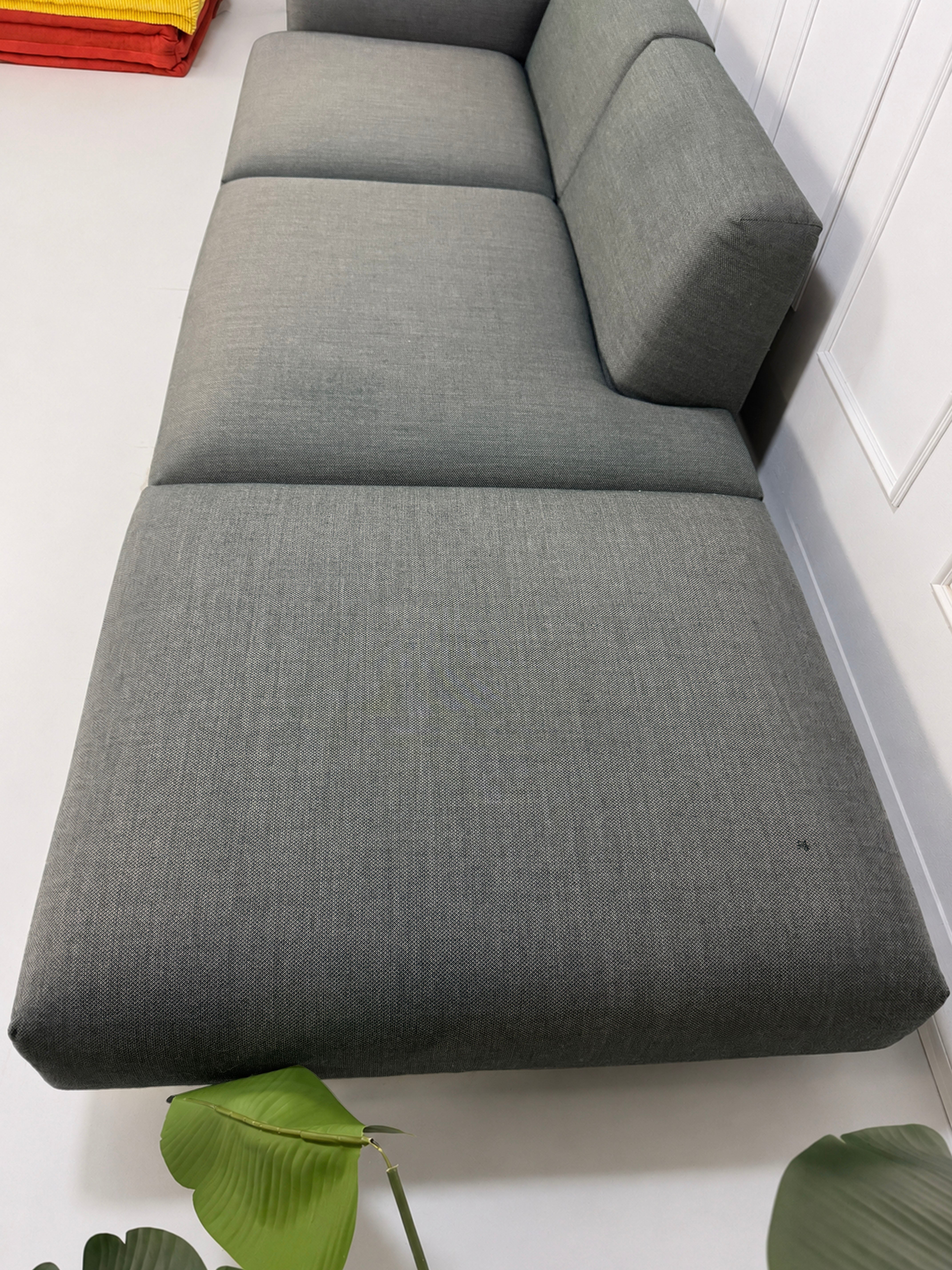 Gebrauchtes graues Muuto In Situ Designer Stoff Sofa vor einer Wand, stilvoll und modern eingerichtet.