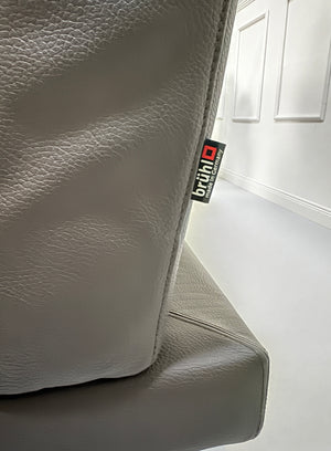 Gebrauchtes braunes Brühl Moule Designer Leder Sofa vor einer Wand, stilvoll und modern eingerichtet.