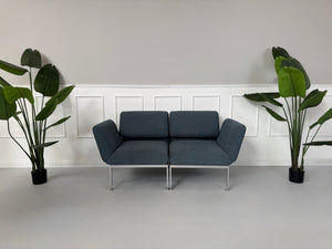 Gebrauchtes grau-blaues Brühl Roro Small Designer Stoff Sofa vor einer Wand, stilvoll und modern eingerichtet.