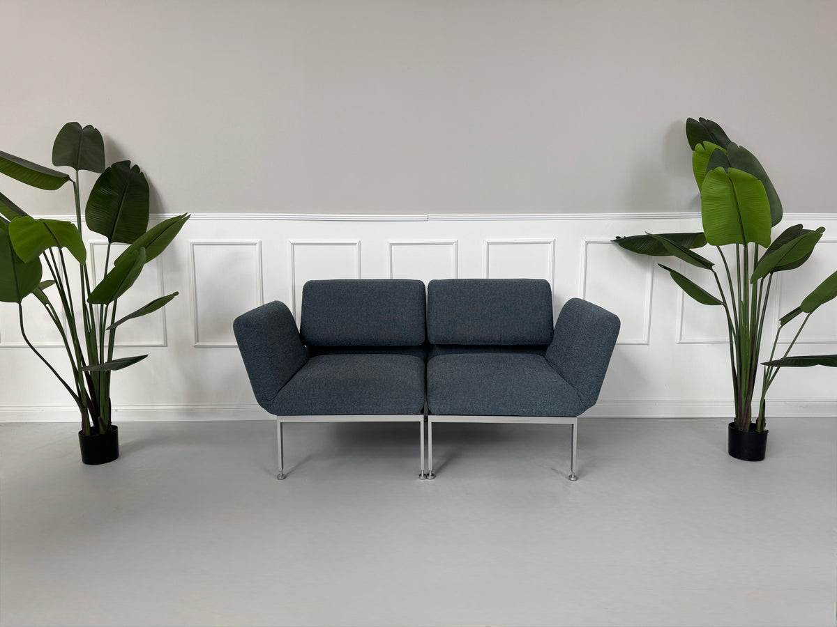 Gebrauchtes grau-blaues Brühl Roro Small Designer Stoff Sofa vor einer Wand, stilvoll und modern eingerichtet.