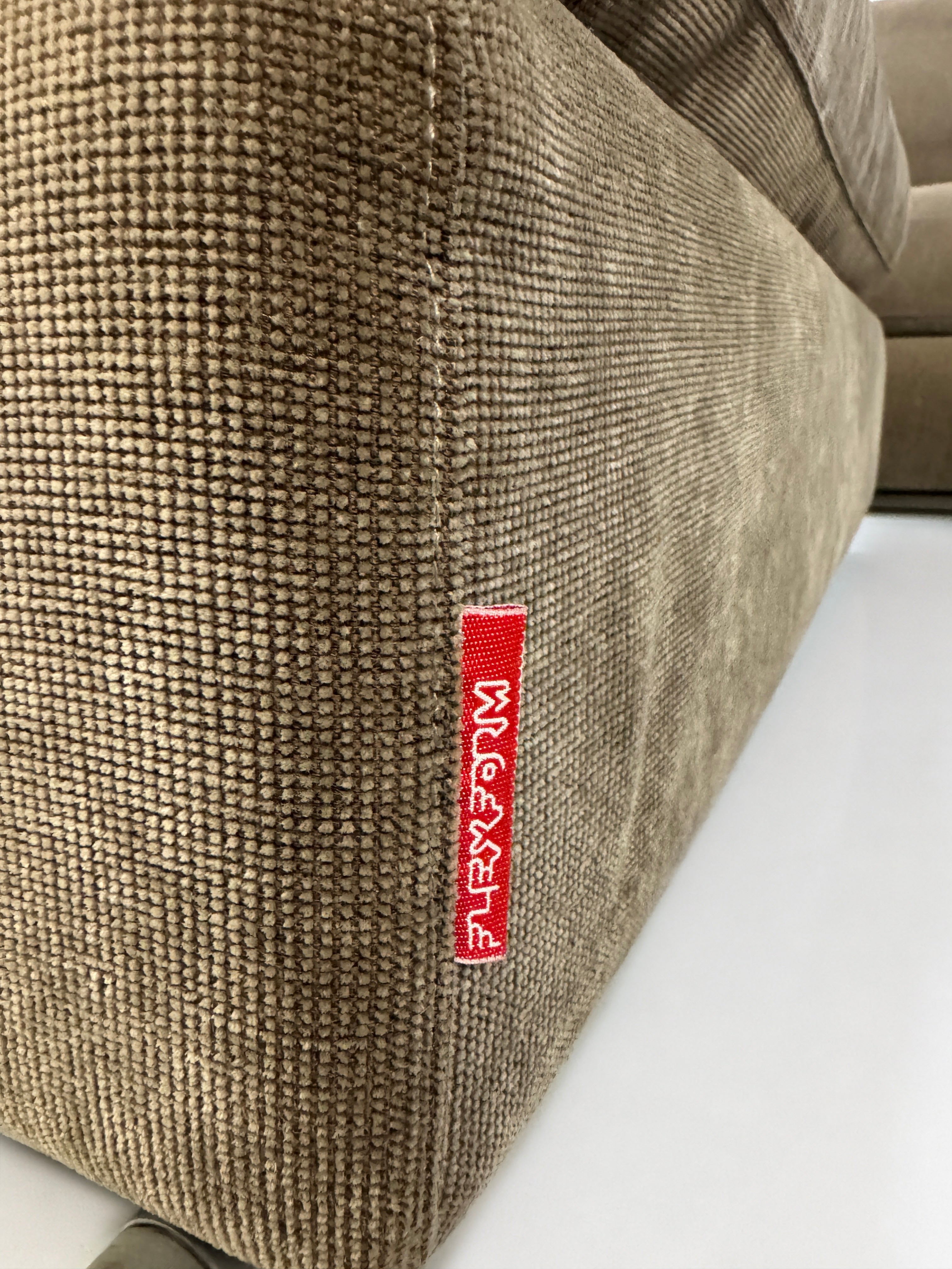 Gebrauchtes braunes Flexform Groundpiece Designer Stoff Sofa vor einer Wand, stilvoll und modern eingerichtet.