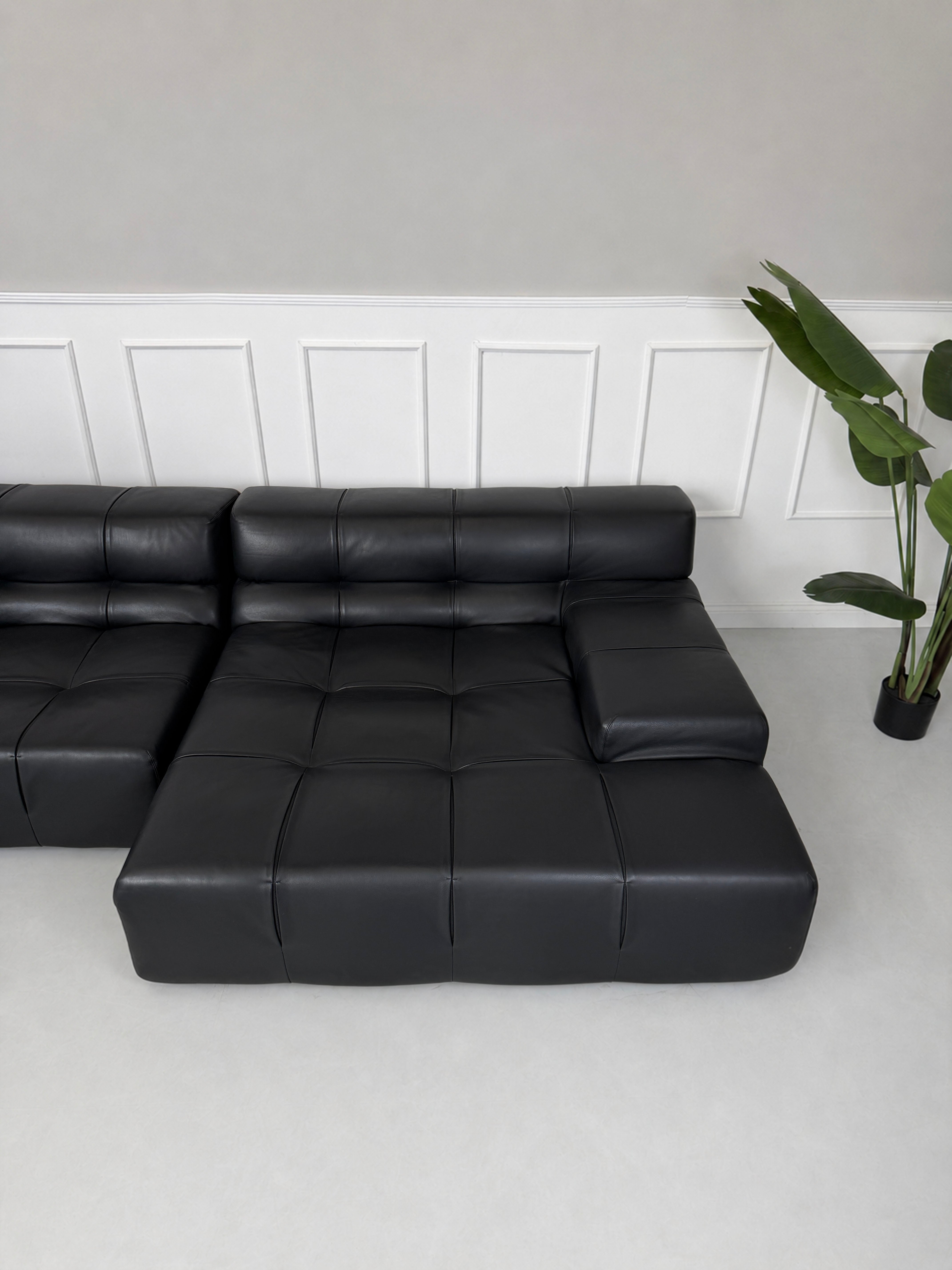 Gebrauchtes schwarzes B&B Italia Tufty Time Designer Leder Sofa vor einer Wand, stilvoll und modern eingerichtet.
