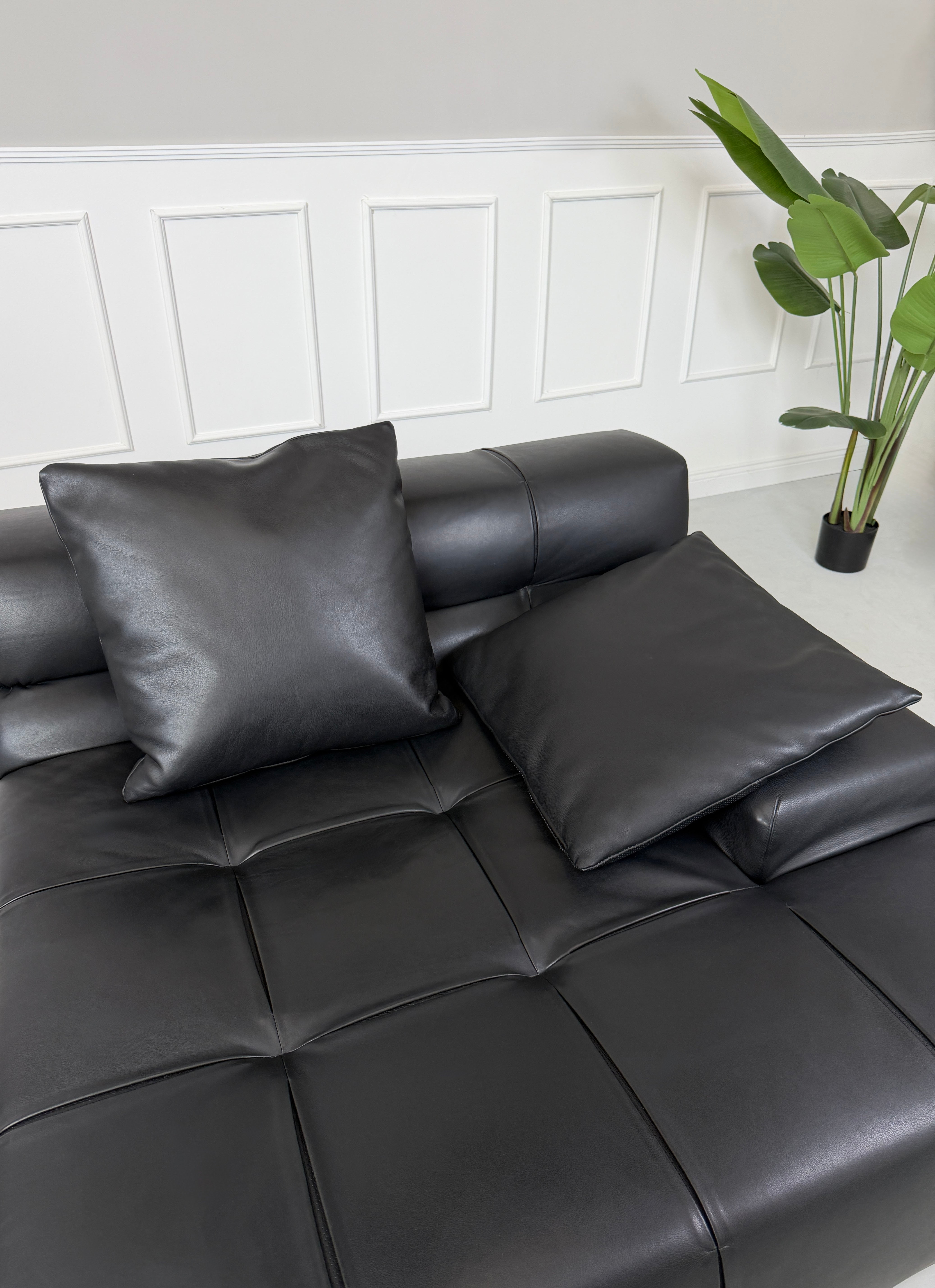 Gebrauchtes schwarzes B&B Italia Tufty Time Designer Leder Sofa vor einer Wand, stilvoll und modern eingerichtet.