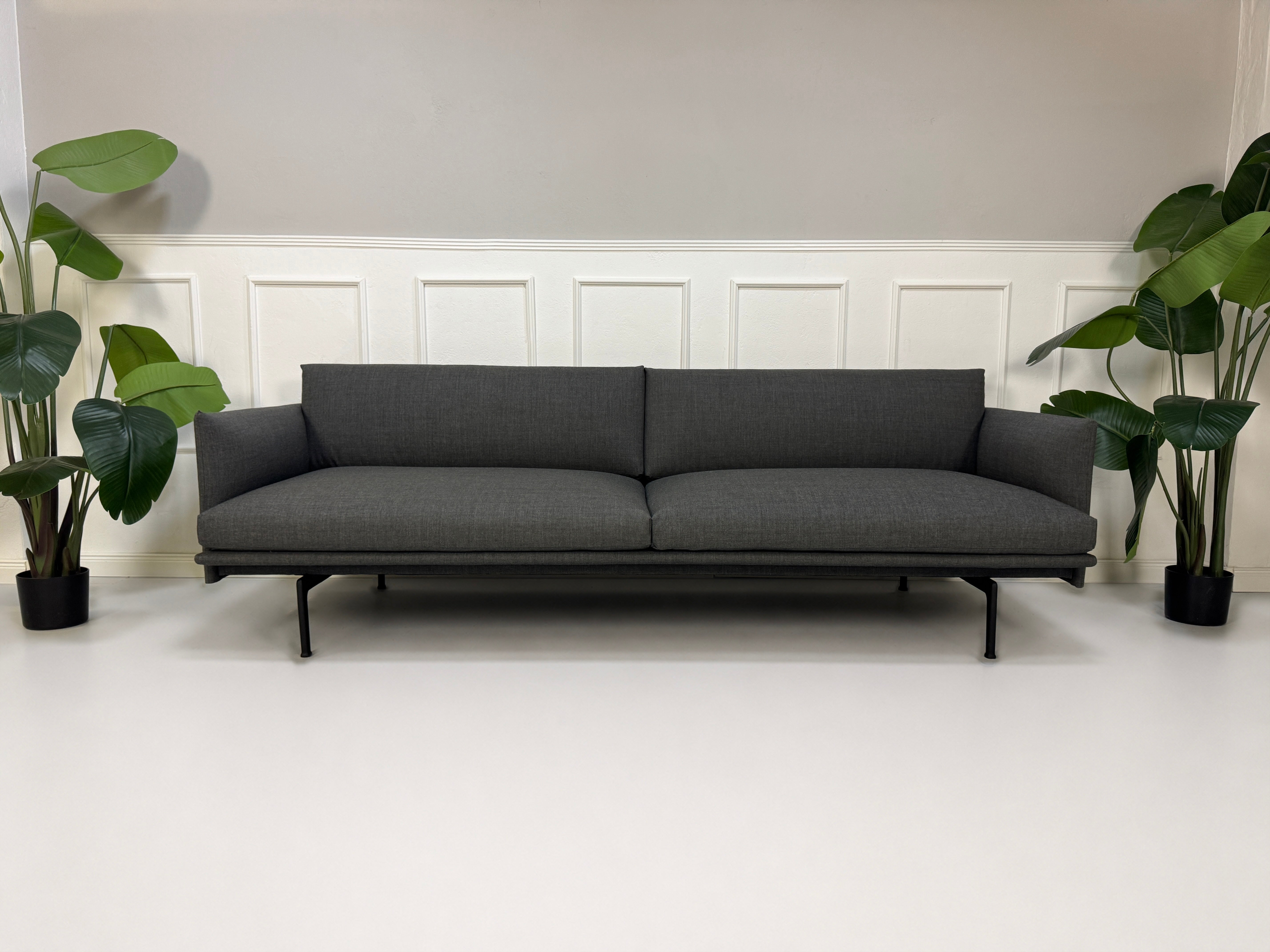 Gebrauchtes graues Muuto Outline Designer Stoff Sofa vor einer Wand, stilvoll und modern eingerichtet.