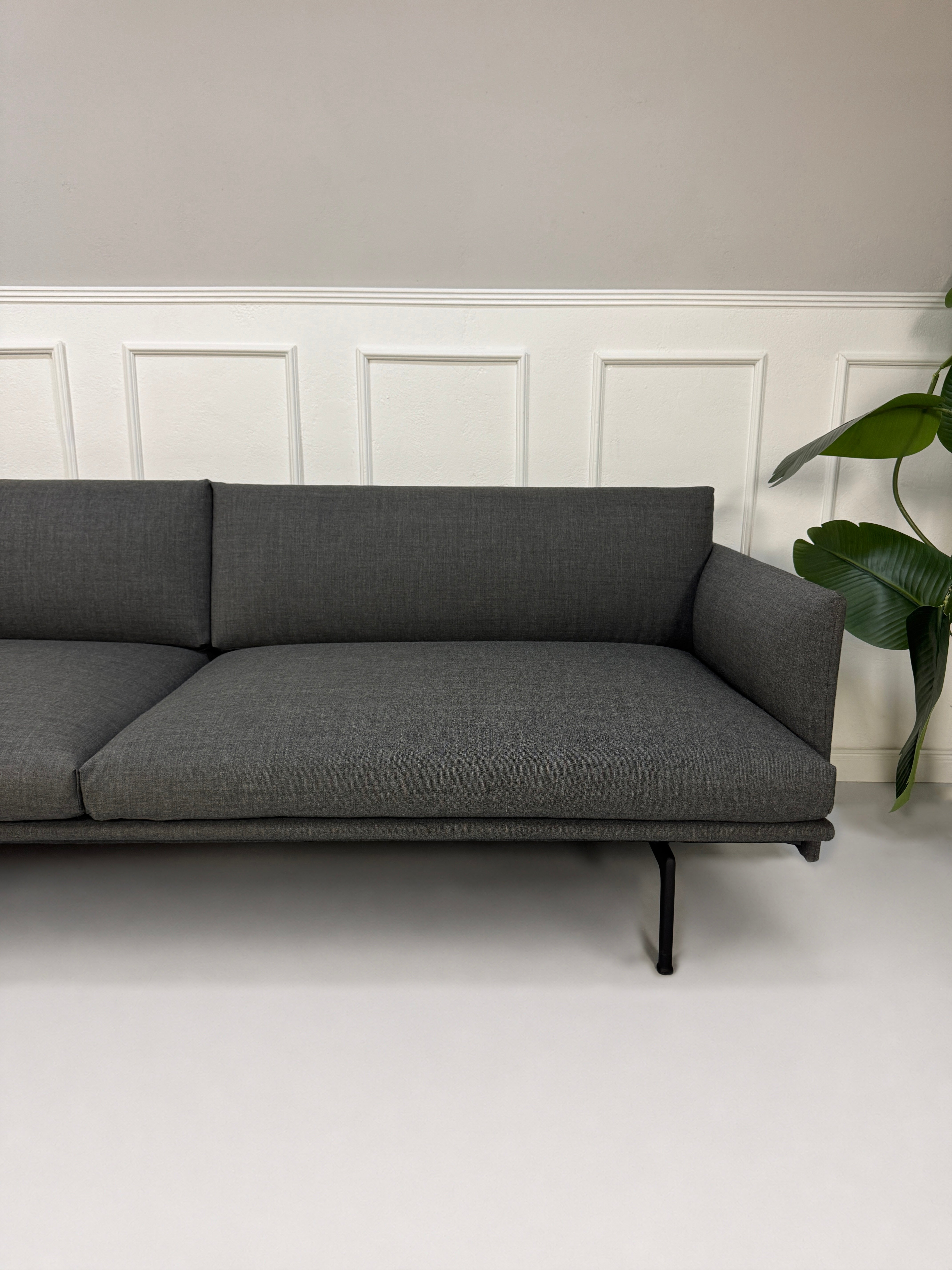 Gebrauchtes graues Muuto Outline Designer Stoff Sofa vor einer Wand, stilvoll und modern eingerichtet.