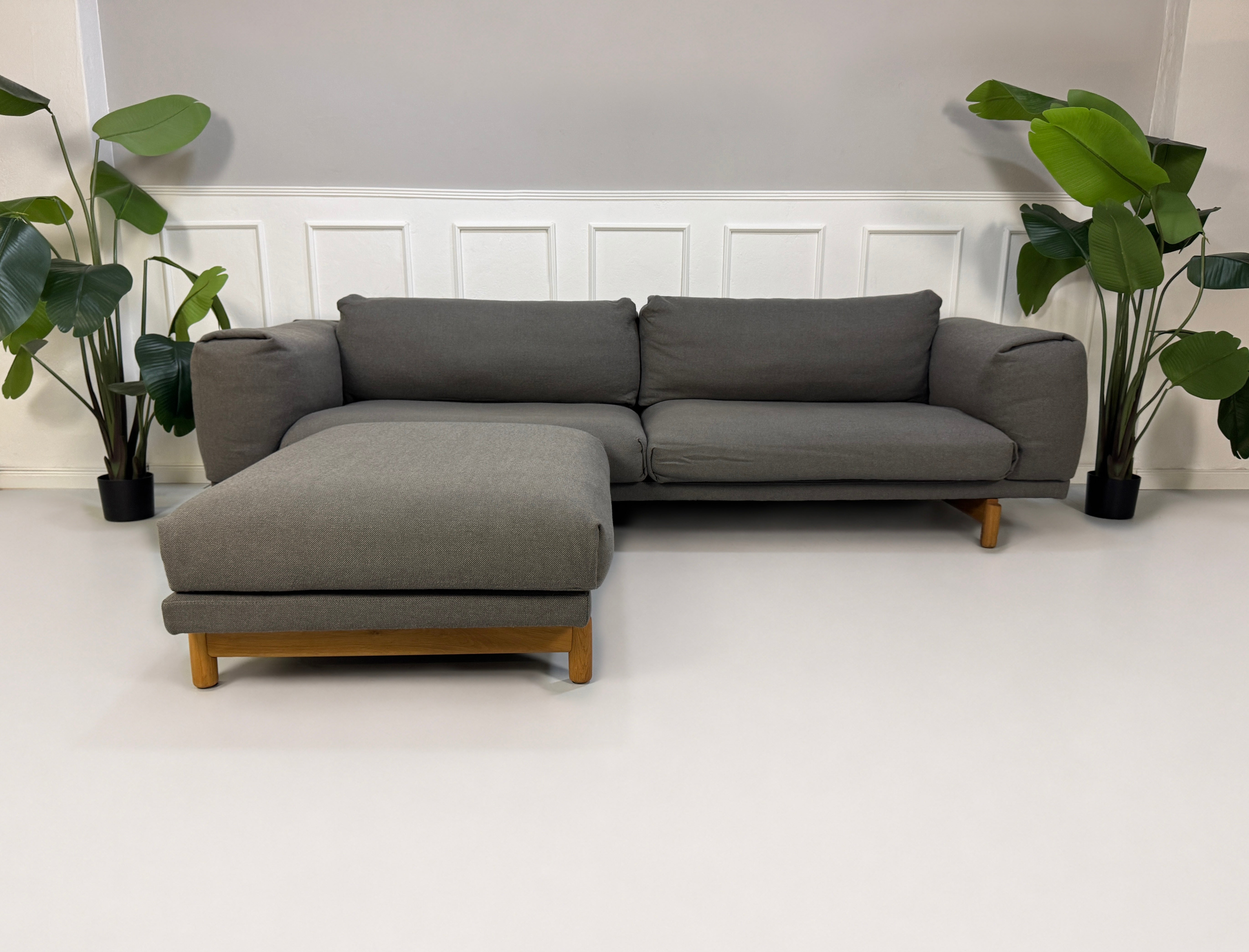 Gebrauchtes graues Muuto Rest Designer Stoff Sofa mit Hocker vor einer Wand, stilvoll und modern eingerichtet.