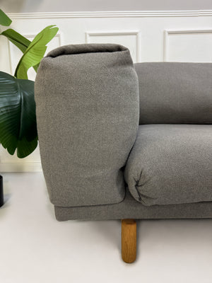 Gebrauchtes graues Muuto Rest Designer Stoff Sofa mit Hocker vor einer Wand, stilvoll und modern eingerichtet.