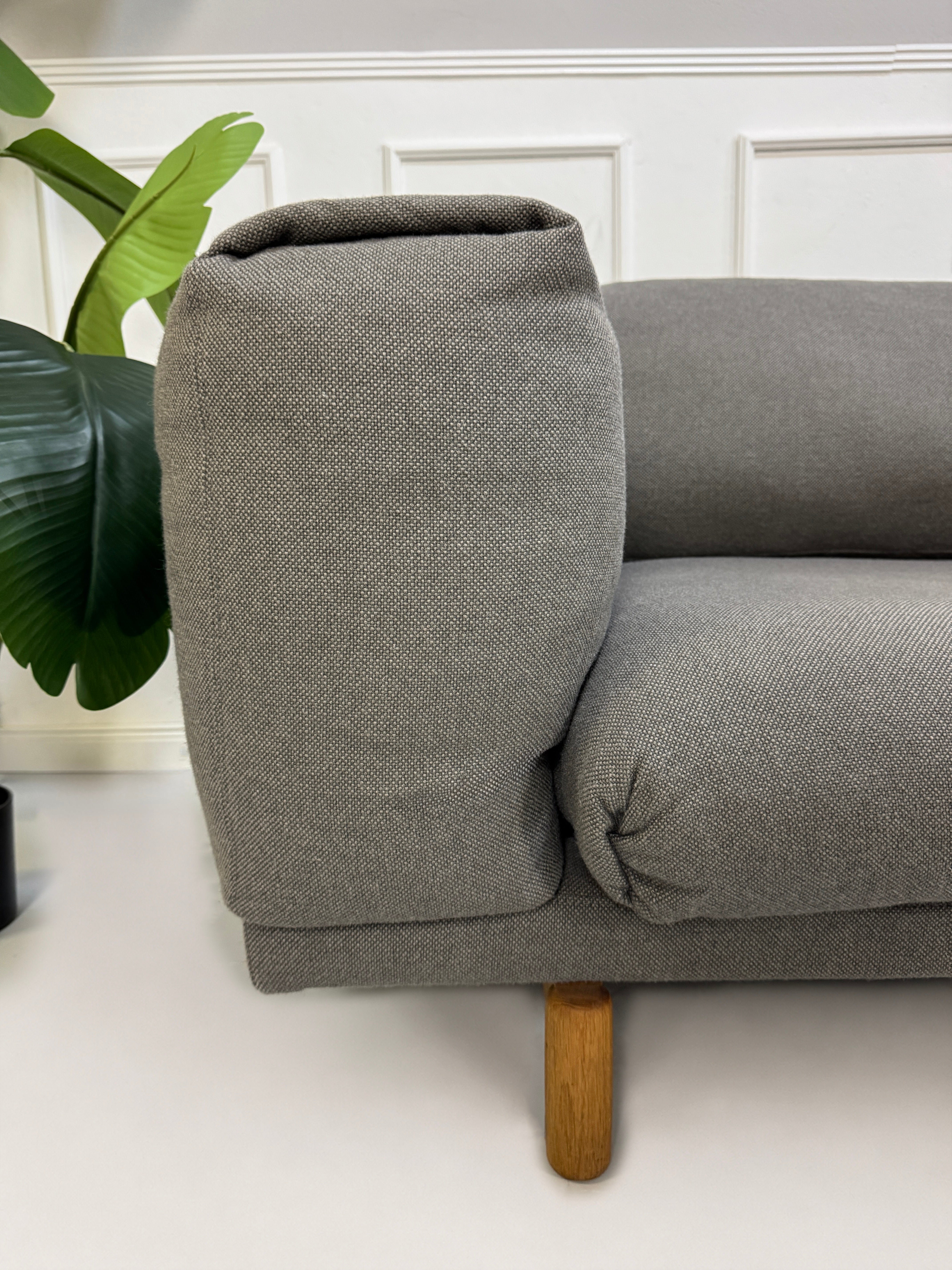 Gebrauchtes graues Muuto Rest Designer Stoff Sofa mit Hocker vor einer Wand, stilvoll und modern eingerichtet.