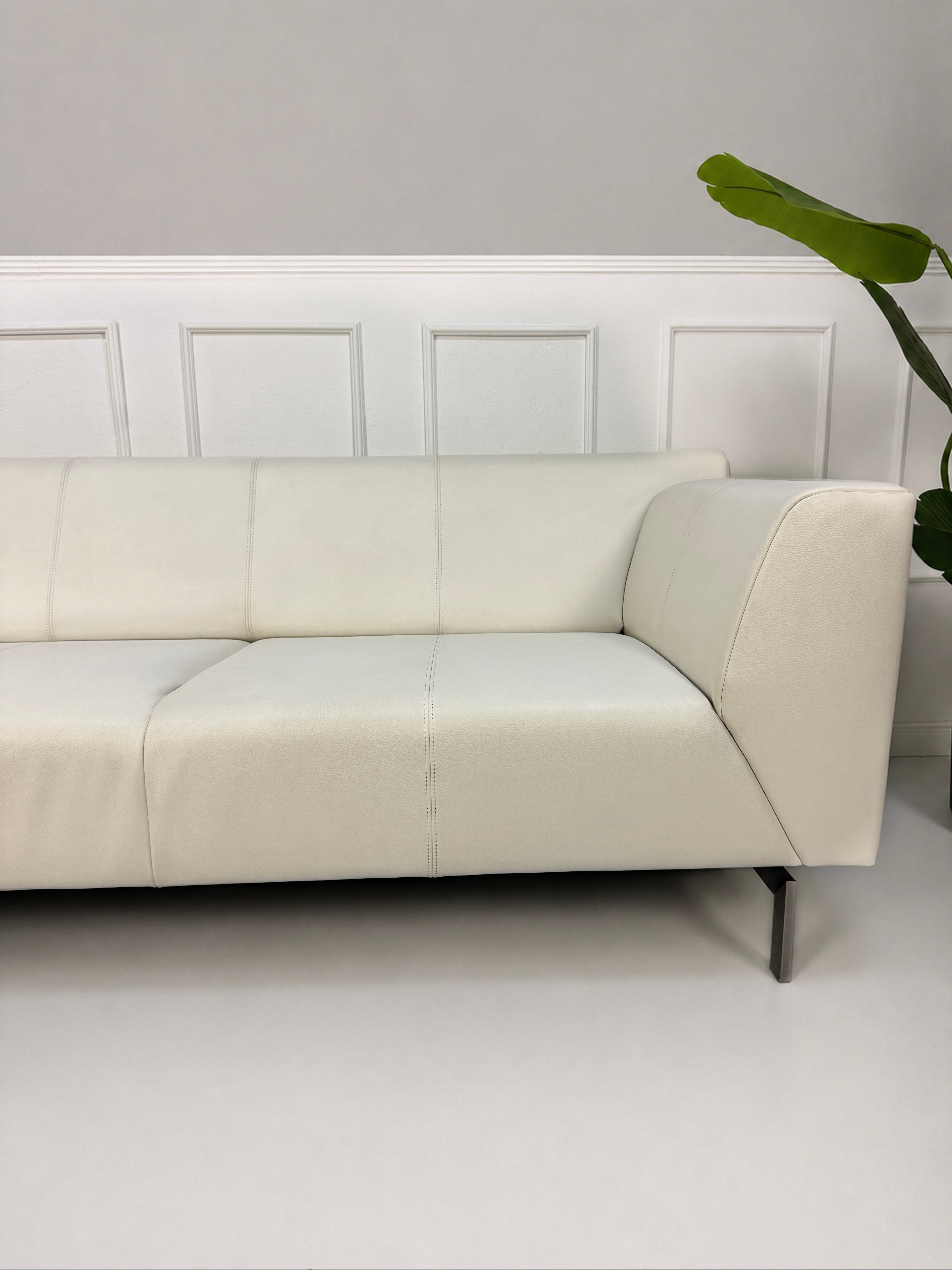 Gebrauchtes weißes Rolf Benz Linea 318 Designer Leder Sofa vor einer Wand, stilvoll und modern eingerichtet.