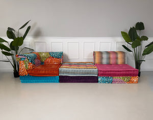 Gebrauchtes buntes Roche Bobois Mah Jong Modulsofa in Missoni-Stoffen, frontal als Sitzreihe vor einer weißen Wand aufgestellt.