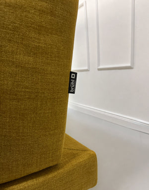 Gebrauchtes gelbes Brühl Moule Designer Stoff Sofa vor einer Wand, stilvoll und modern eingerichtet.