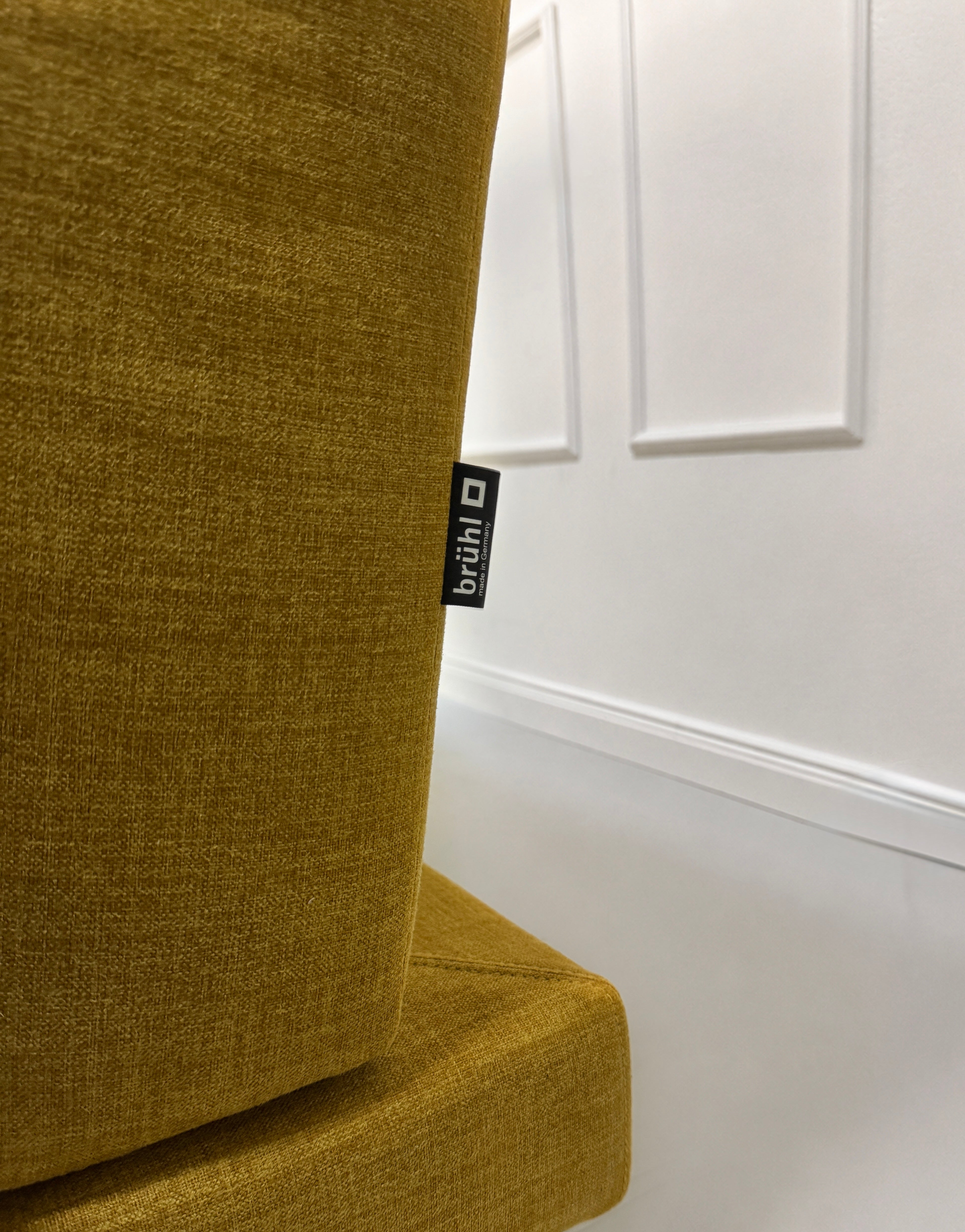Gebrauchtes gelbes Brühl Moule Designer Stoff Sofa vor einer Wand, stilvoll und modern eingerichtet.