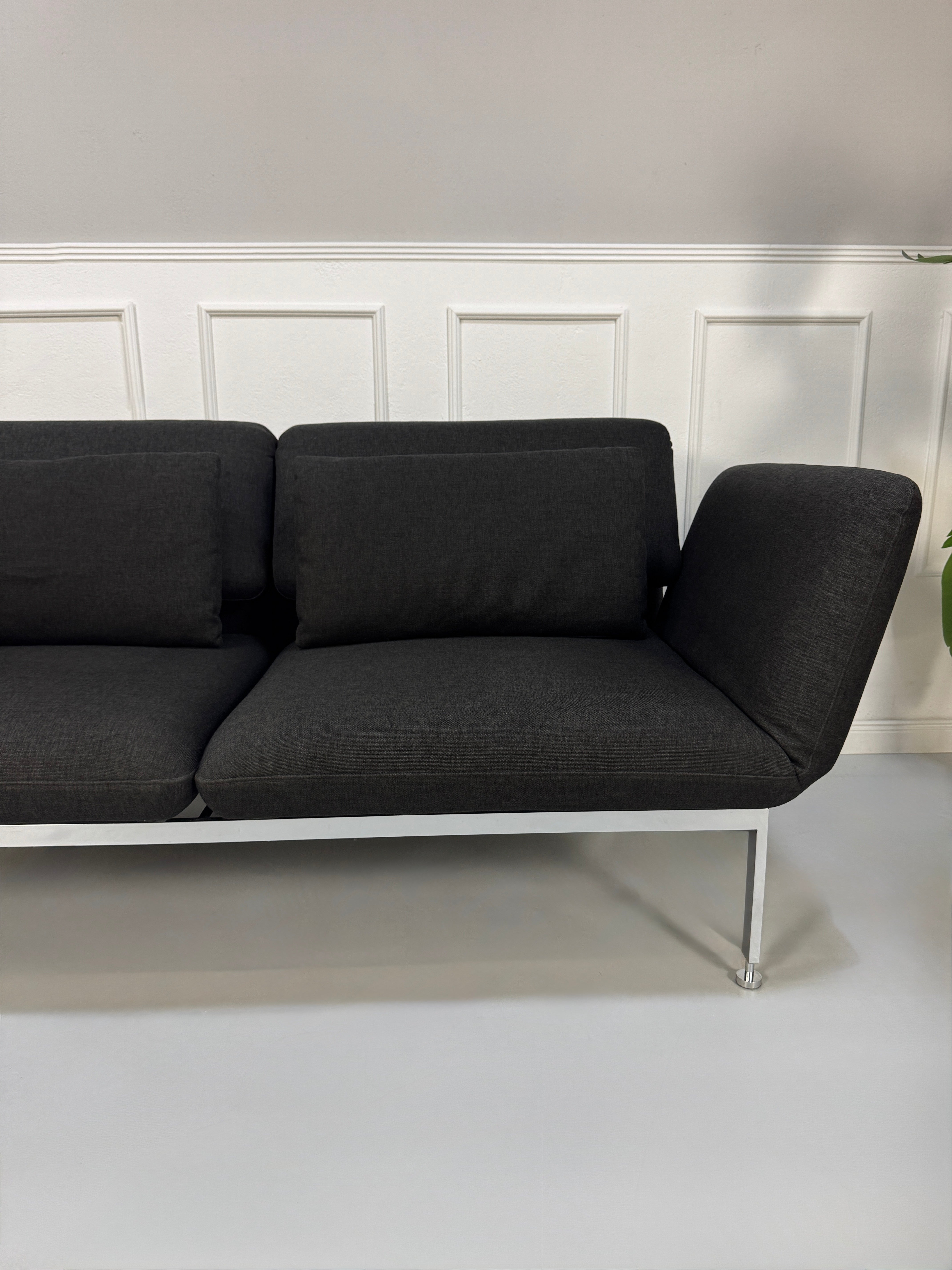 Gebrauchtes graues Brühl Roro Designer Stoff Sofa vor einer Wand, stilvoll und modern eingerichtet.