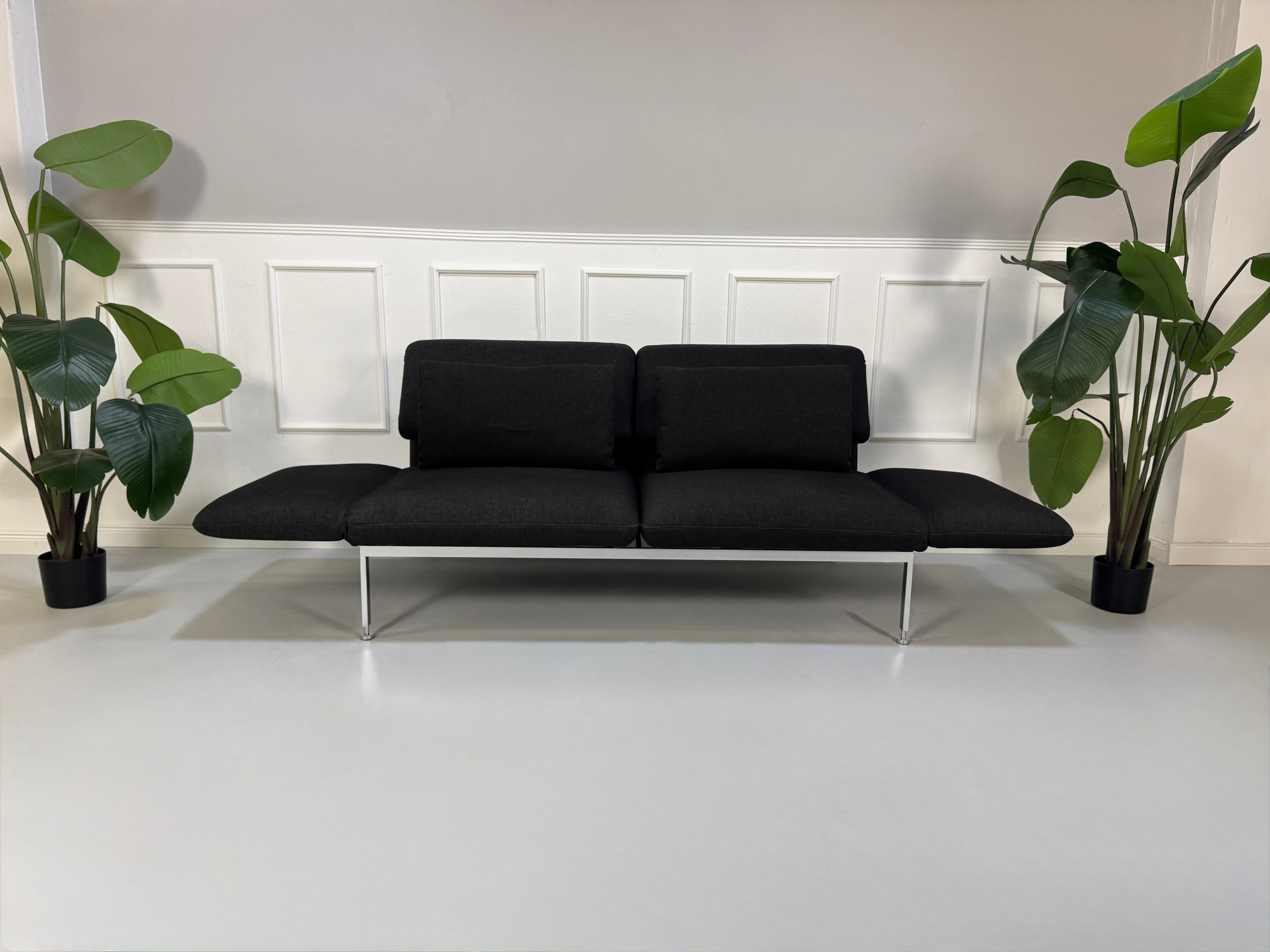 Gebrauchtes graues Brühl Roro Designer Stoff Sofa vor einer Wand, stilvoll und modern eingerichtet.