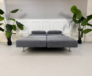 Gebrauchtes graues Brühl Moule Designer Stoff Sofa vor einer Wand, stilvoll und modern eingerichtet.